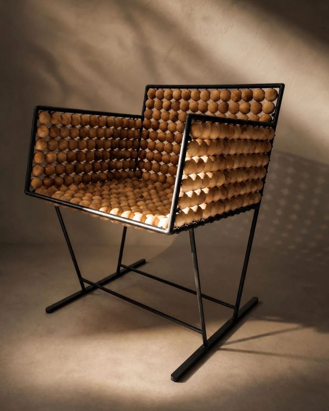 Modern chair made with black metal frame and wooden rounded beads forming the seat and backrest, placed against a neutral background with soft lighting.