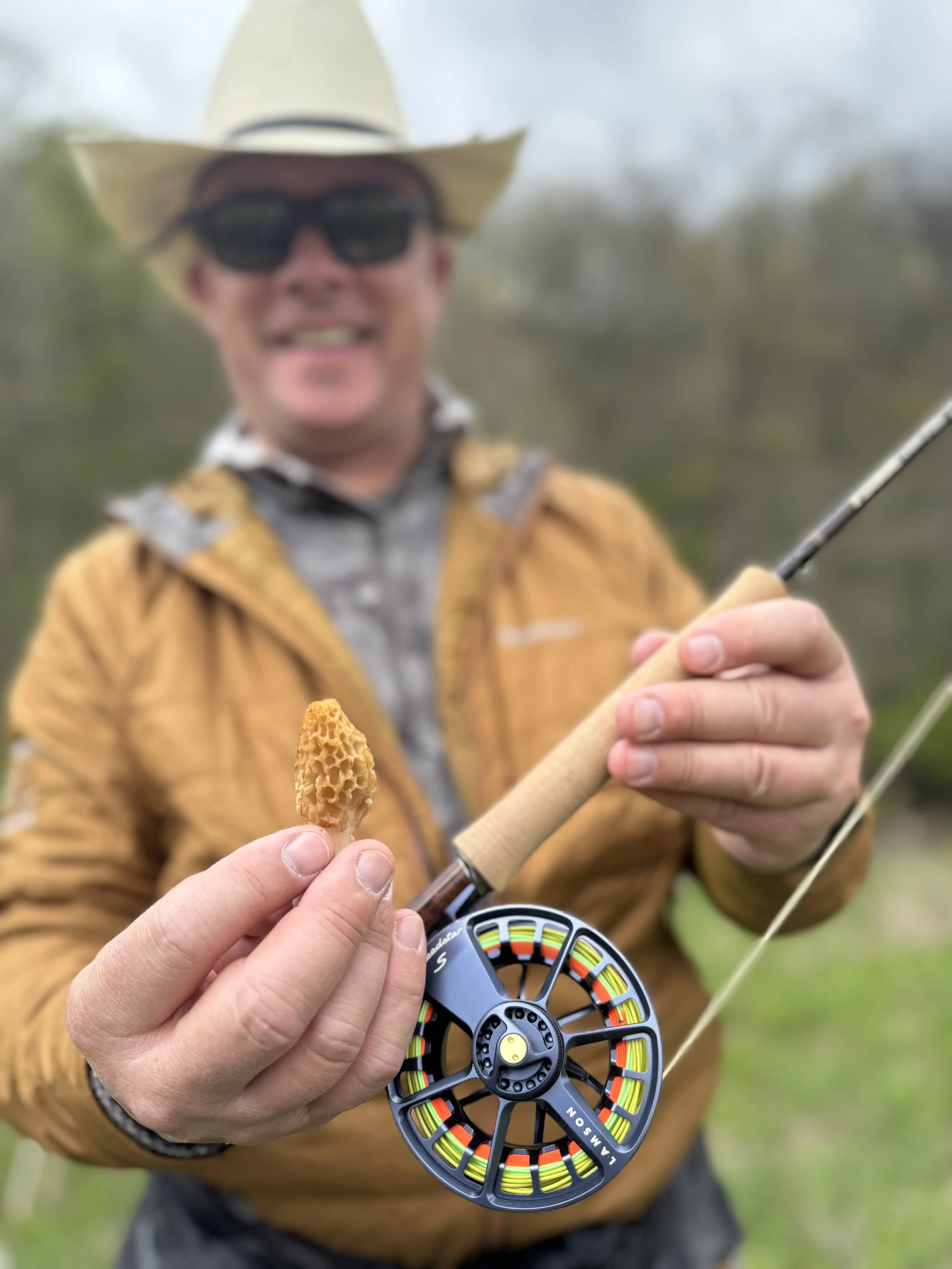 Guided angler holding up a morel and a flyrod at BEAC Trout Camp