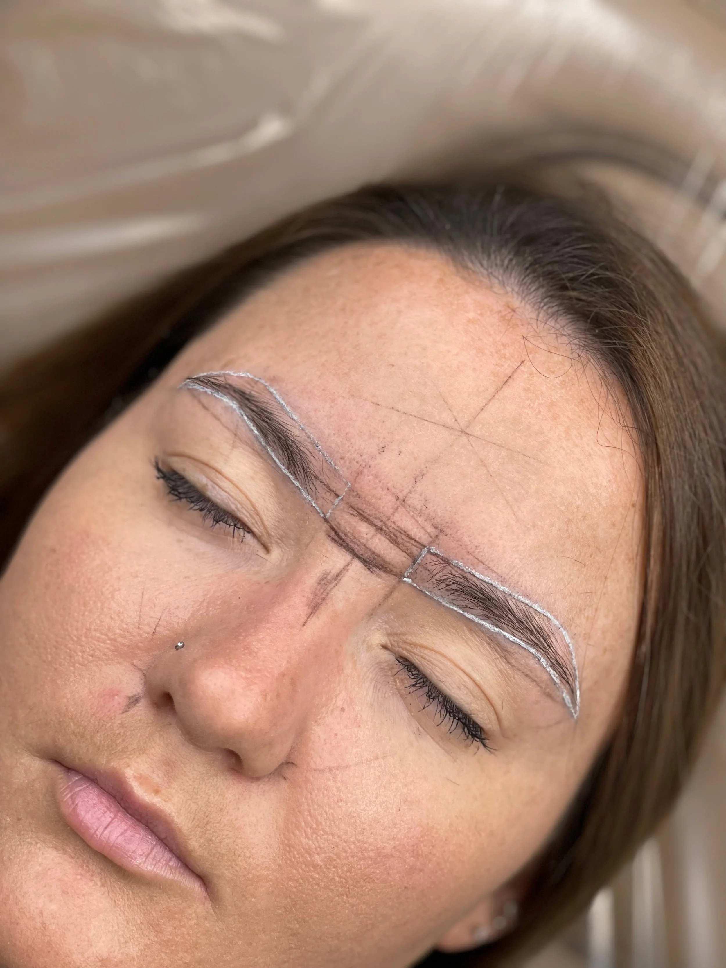 Brow mapping guidelines drawn before permanent makeup application.