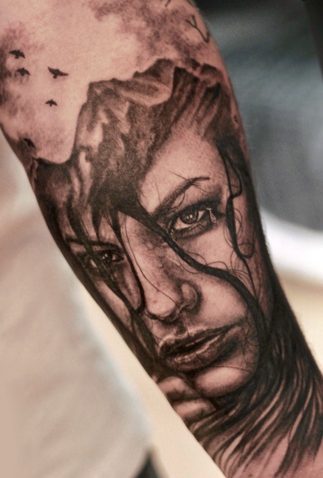 Black-and-grey portrait of a woman blended with mountain scenery and flying birds, tattoo by Colina at Stella Tattoo.