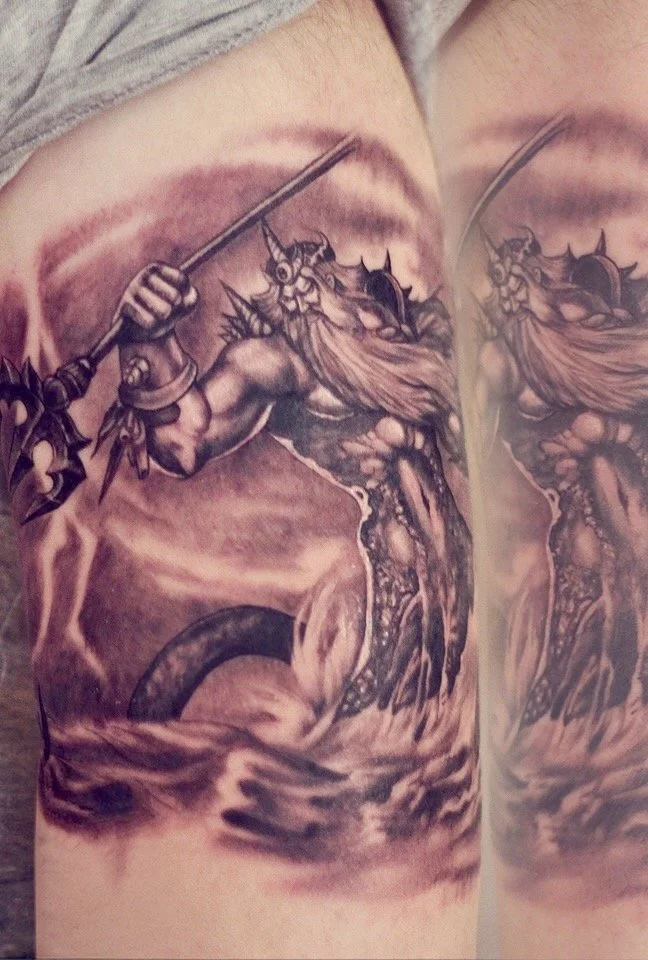Black-and-grey fantasy warrior tattoo with a raised sword, flowing hair, and dramatic shading, by Colina.