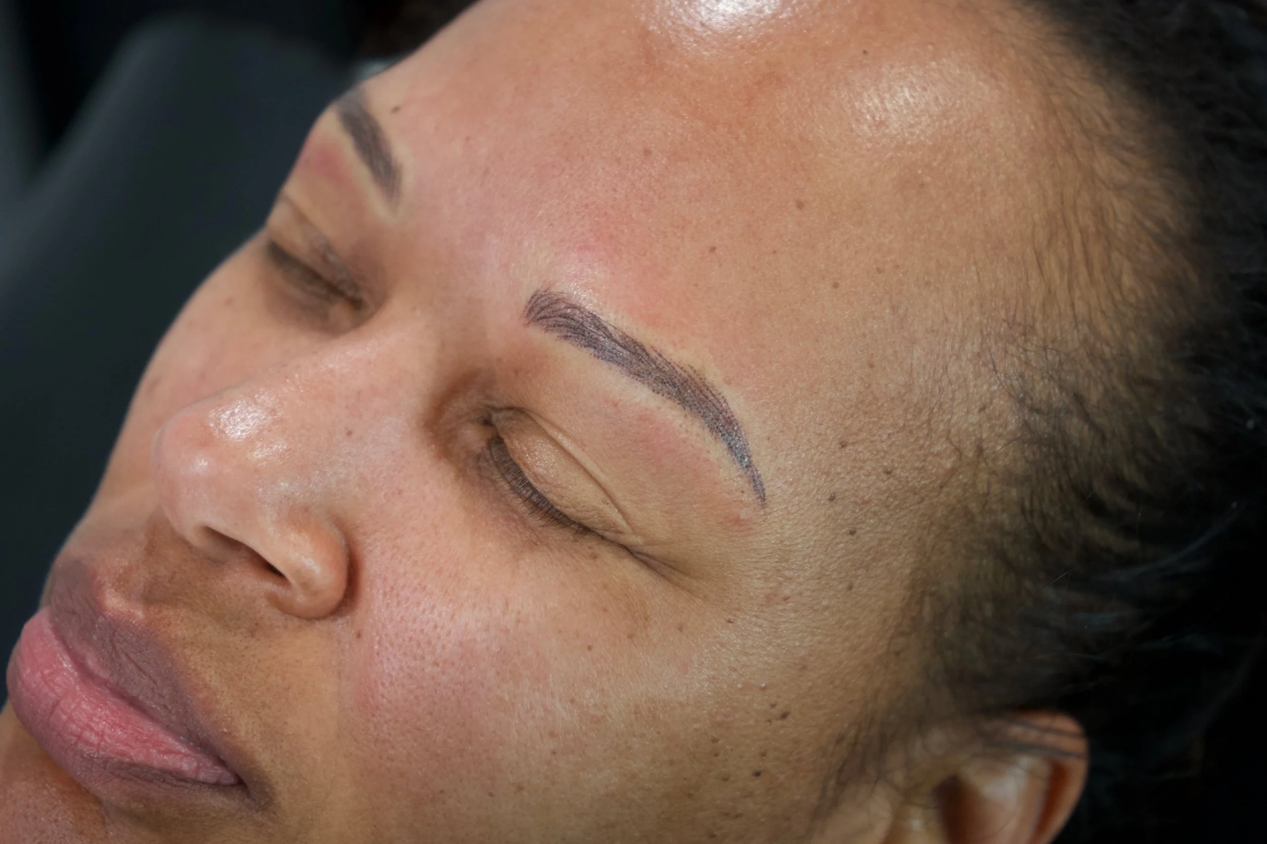 Client shown in profile with softly defined permanent makeup brows.