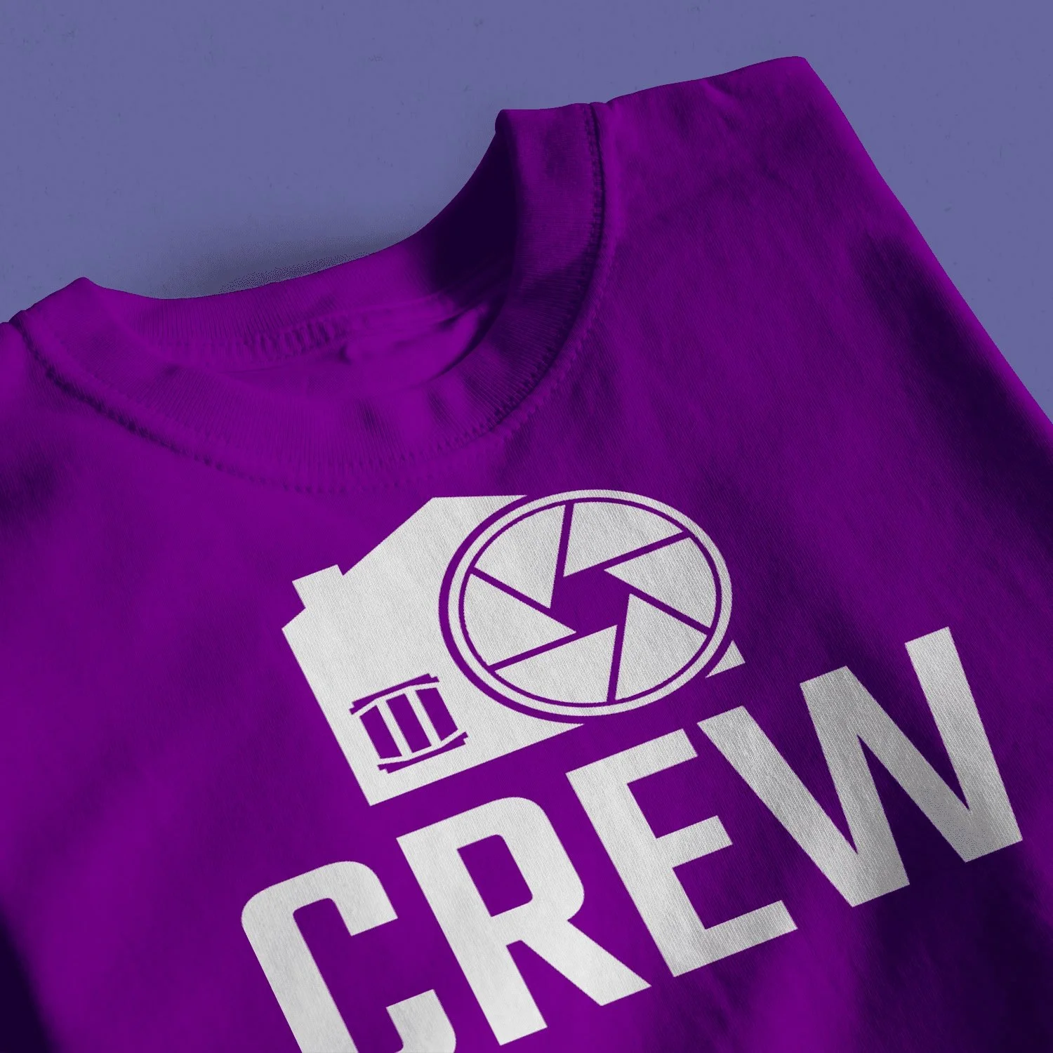 Purple T-shirt with a white graphic of a camera lens and the word "CREW" printed on it.
