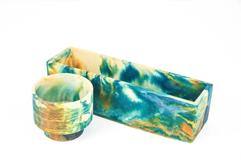 A set of two planters, one rectangular and one cylindrical, featuring a marbled design with green, blue, yellow, and orange colors.