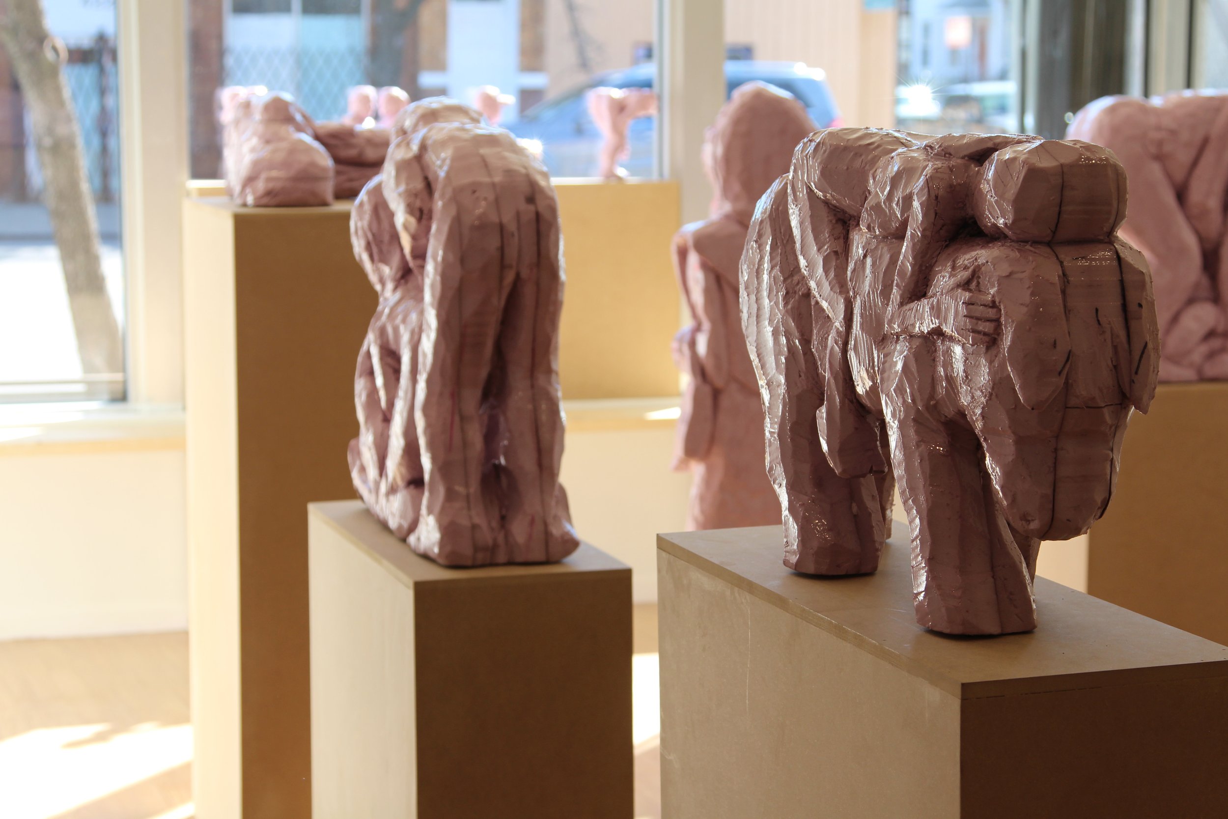 Abstract pink sculptures on pedestals in a gallery.