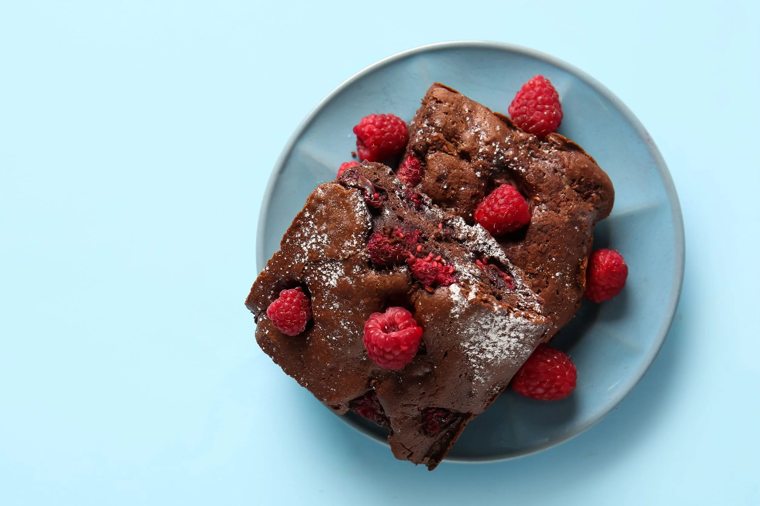 Chocolate loaf cake with raspberries on a blue plate