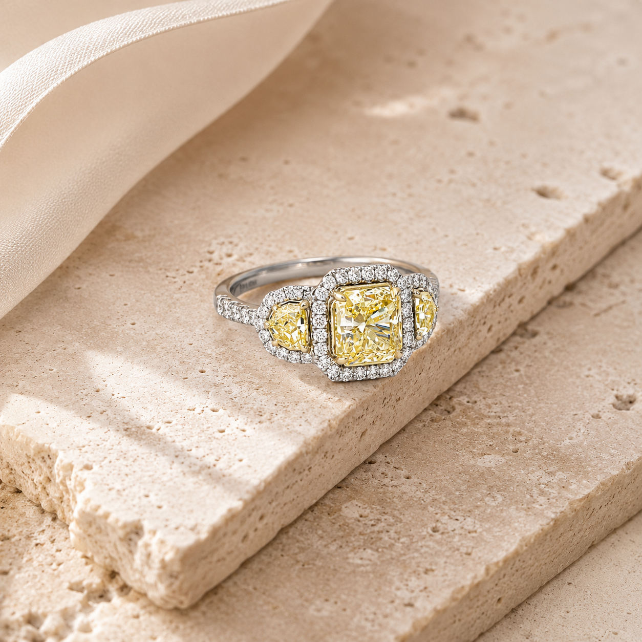 Two-tone gold cushion-cut butter yellow diamond three-stone halo ring from Brilliant Fine+Custom Jewelry