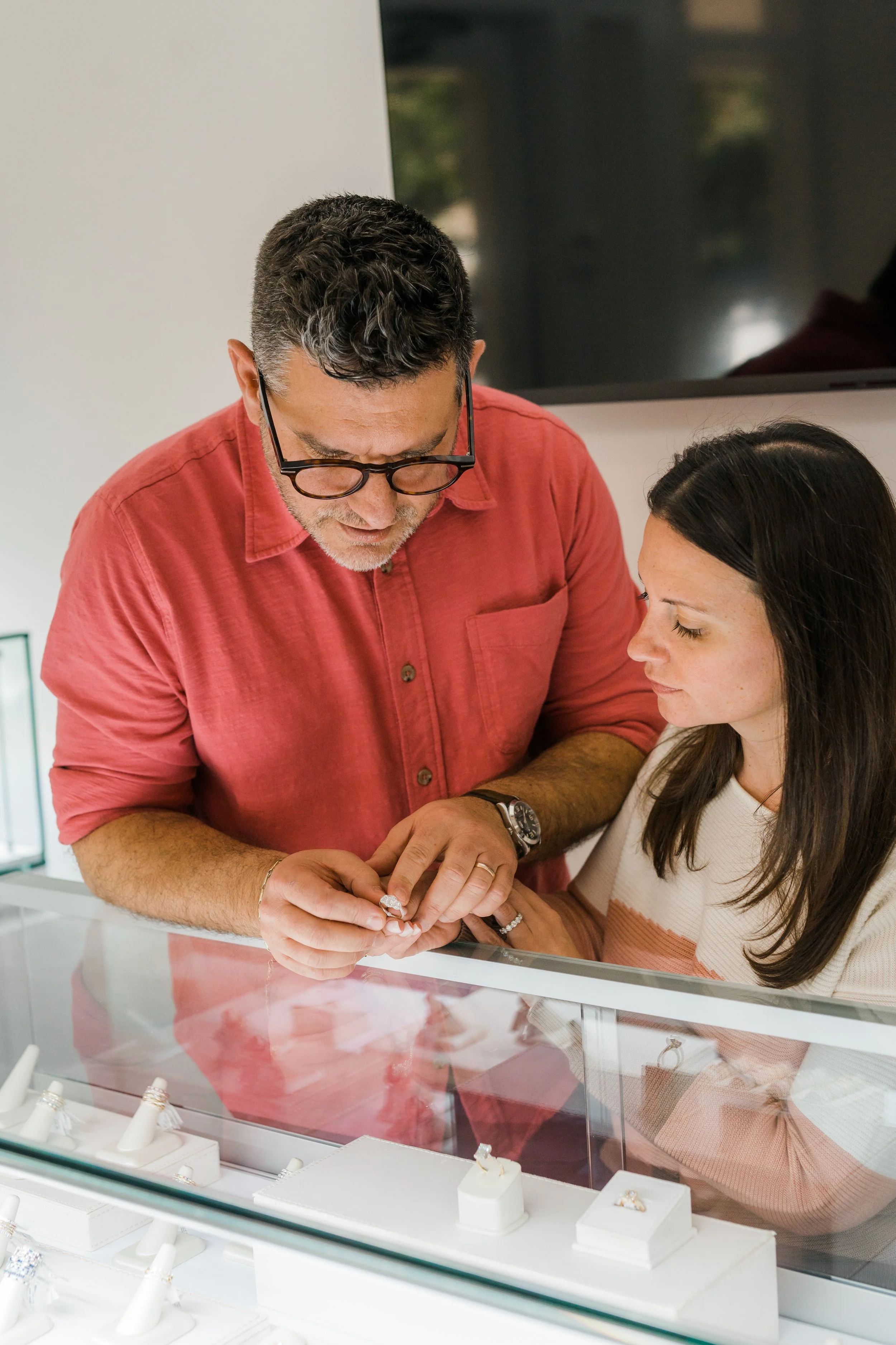 A photo of Katie and Jamie Jaffe examining a diamond ring at one of the curated display cases in Brilliant Fine+Custom Jewelry in Roswell Atlanta