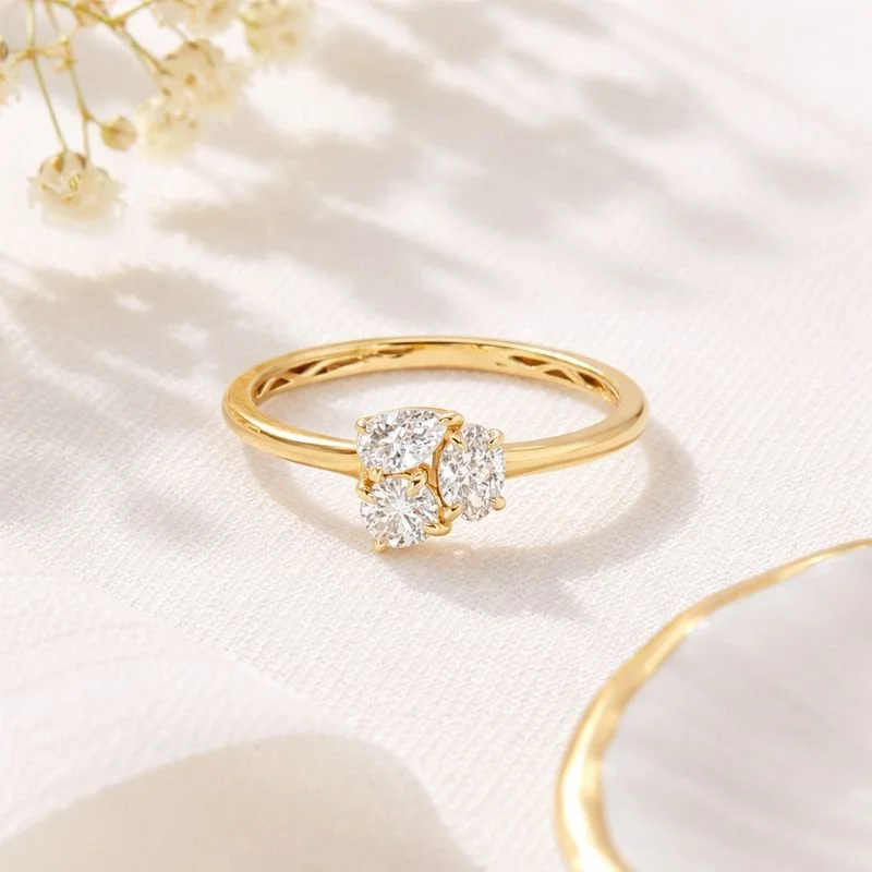 A 14k yellow gold ring featuring a trio of lab-grown diamonds in pear, marquise, and round cuts from Brilliant Fine+Custom Jewelry