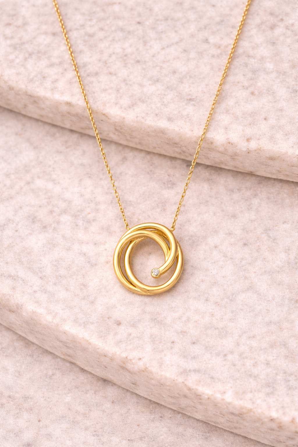 A necklace in 14k yellow gold with a swirl pendant and 0.01 ctw Diamond from Brilliant Fine+Custom Jewelry