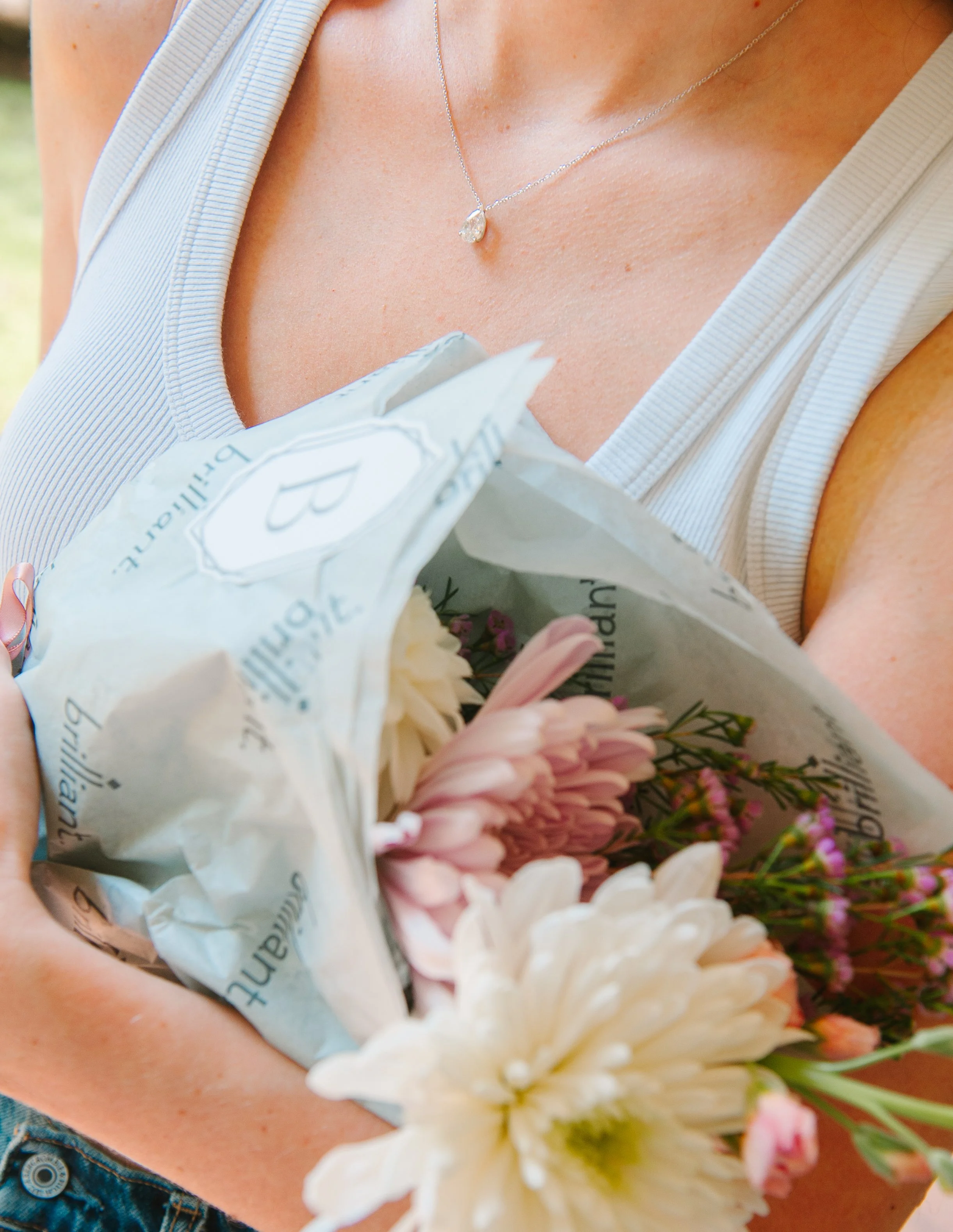 Guest holding a fresh floral bouquet from the Stack Your Story bloom bar while wearing a delicate diamond pendant necklace.