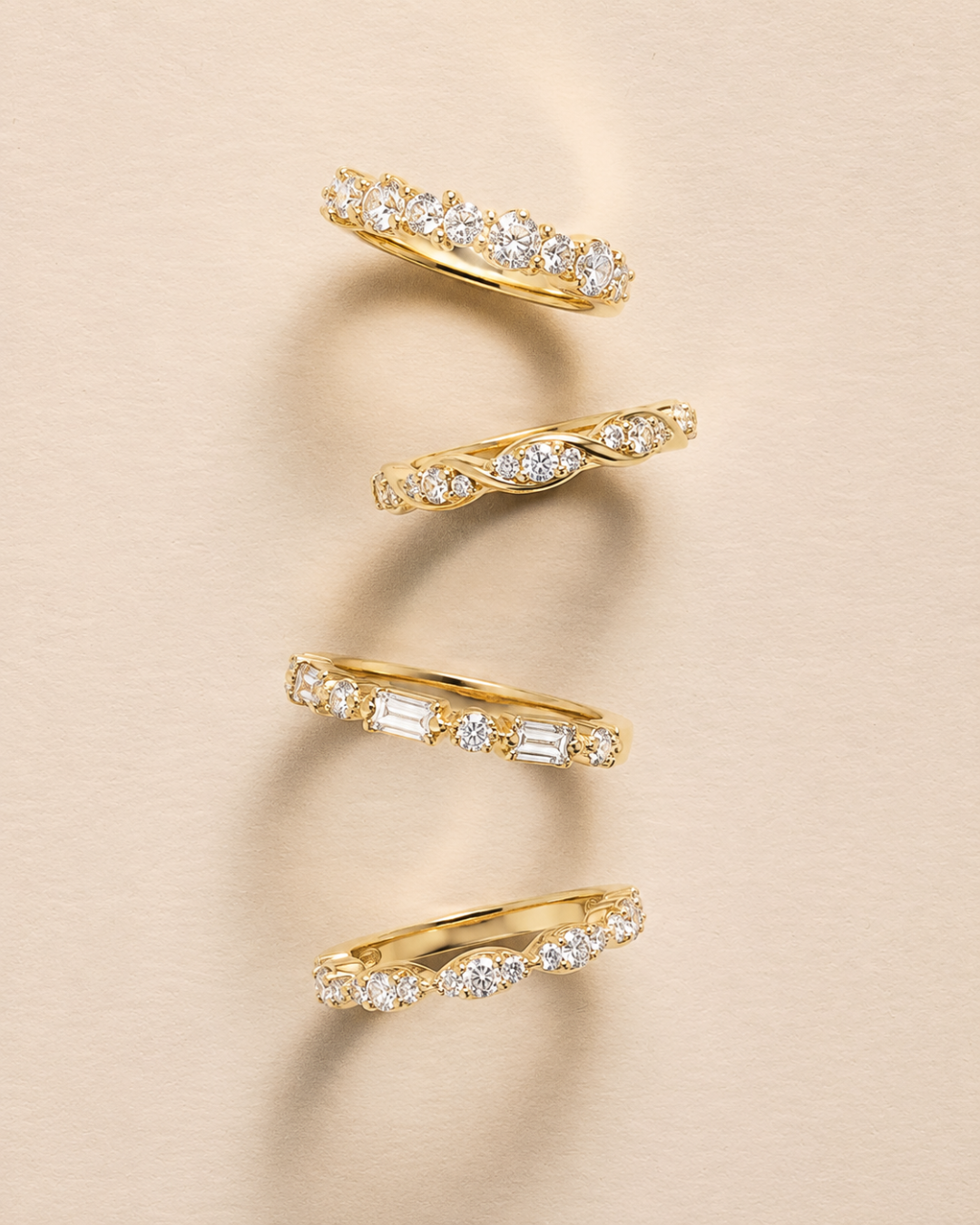 Four Stackable Yellow Gold bands featuring various diamond cuts and settings, available at Brilliant Fine+Custom Jewelry.