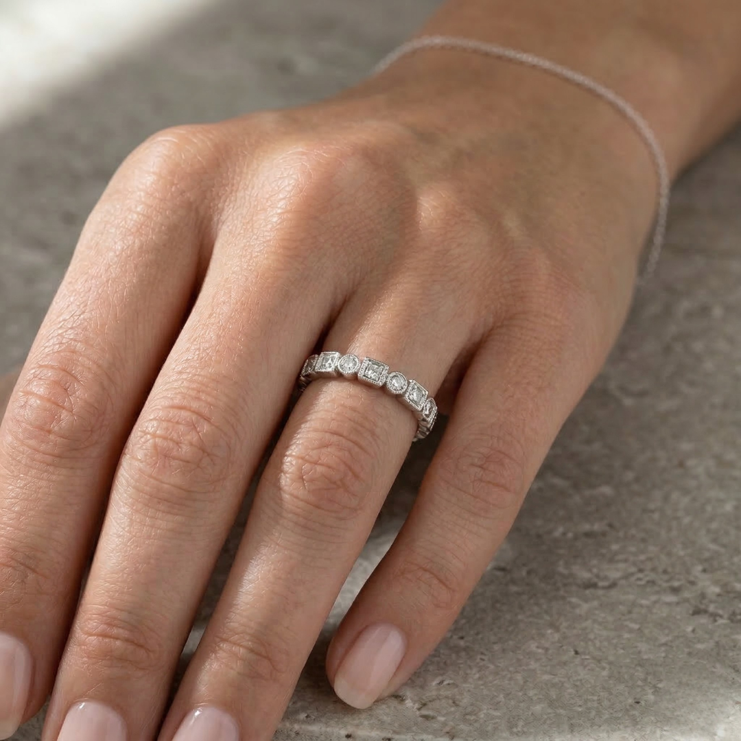 A bezel-set half-diamond band with round and princess-cut diamonds set in white gold from Brilliant Fine+Custom Jewelry
