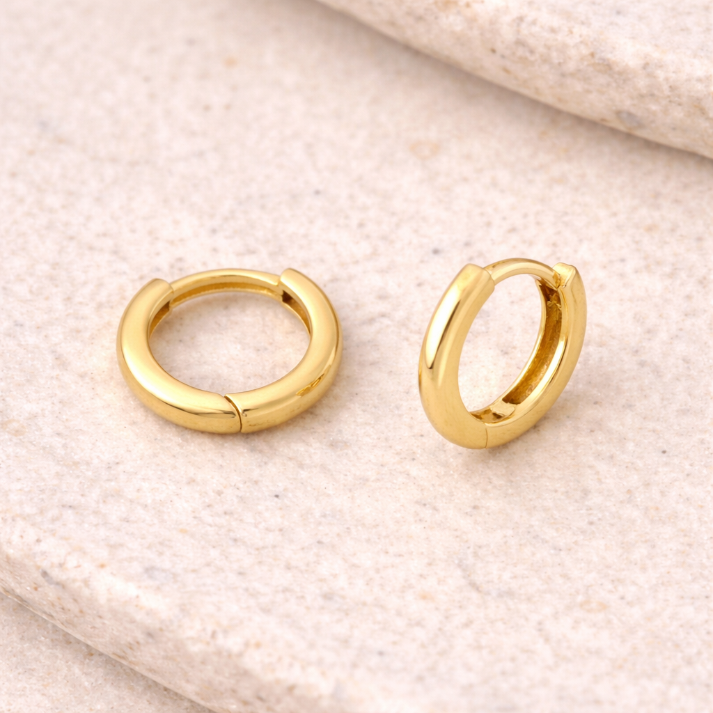 A close up of our 14k Yellow Gold huggie earrings from Brilliant Fine+Custom Jewelry.