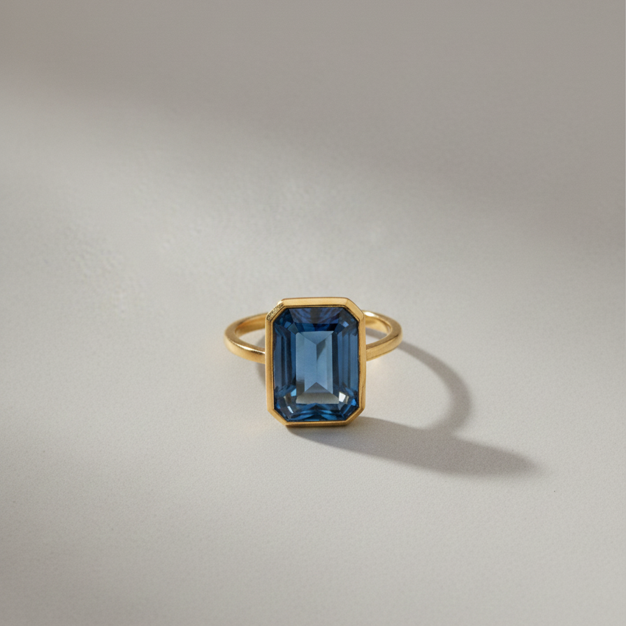 A 14k yellow gold ring with an emerald-cut london blue topaz stone from Brilliant Fine+Custom jewelry.