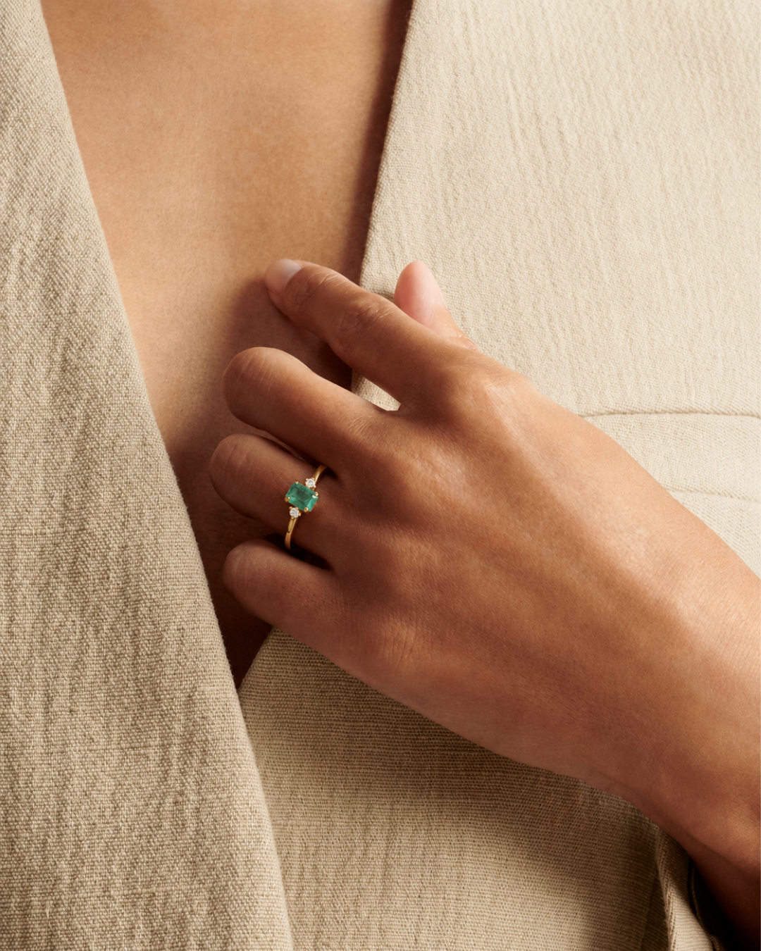 A band with a square-cut emerald with two round diamonds set in yellow gold from Brilliant Fine+Custom