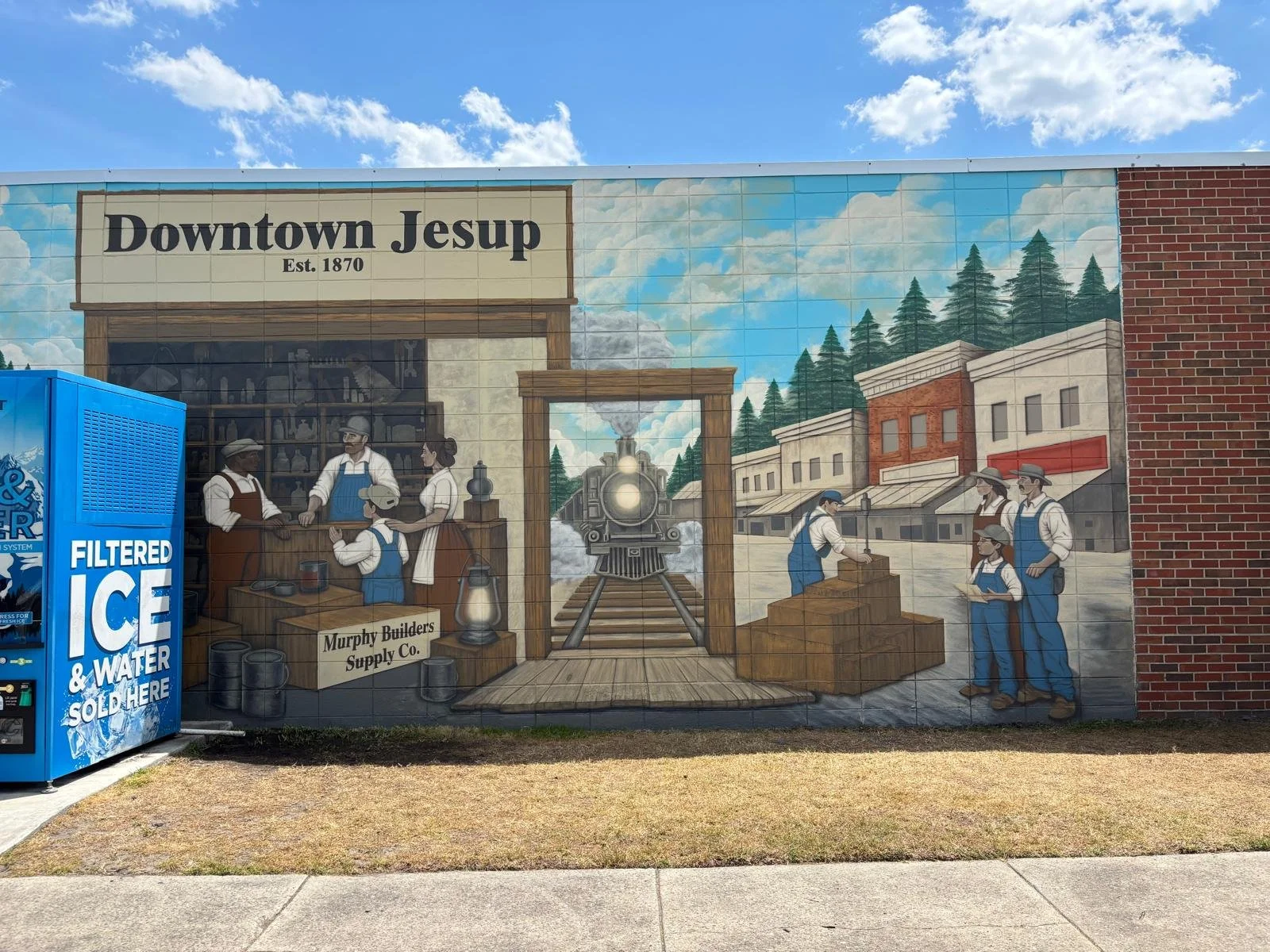 Mural depicting historic downtown Jesup with a train, workers, and buildings, and the sign 'Downtown Jesup Est. 1870'.
