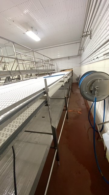 Industrial room with a long metal shelving unit and a blue hose reel mounted on the wall.
