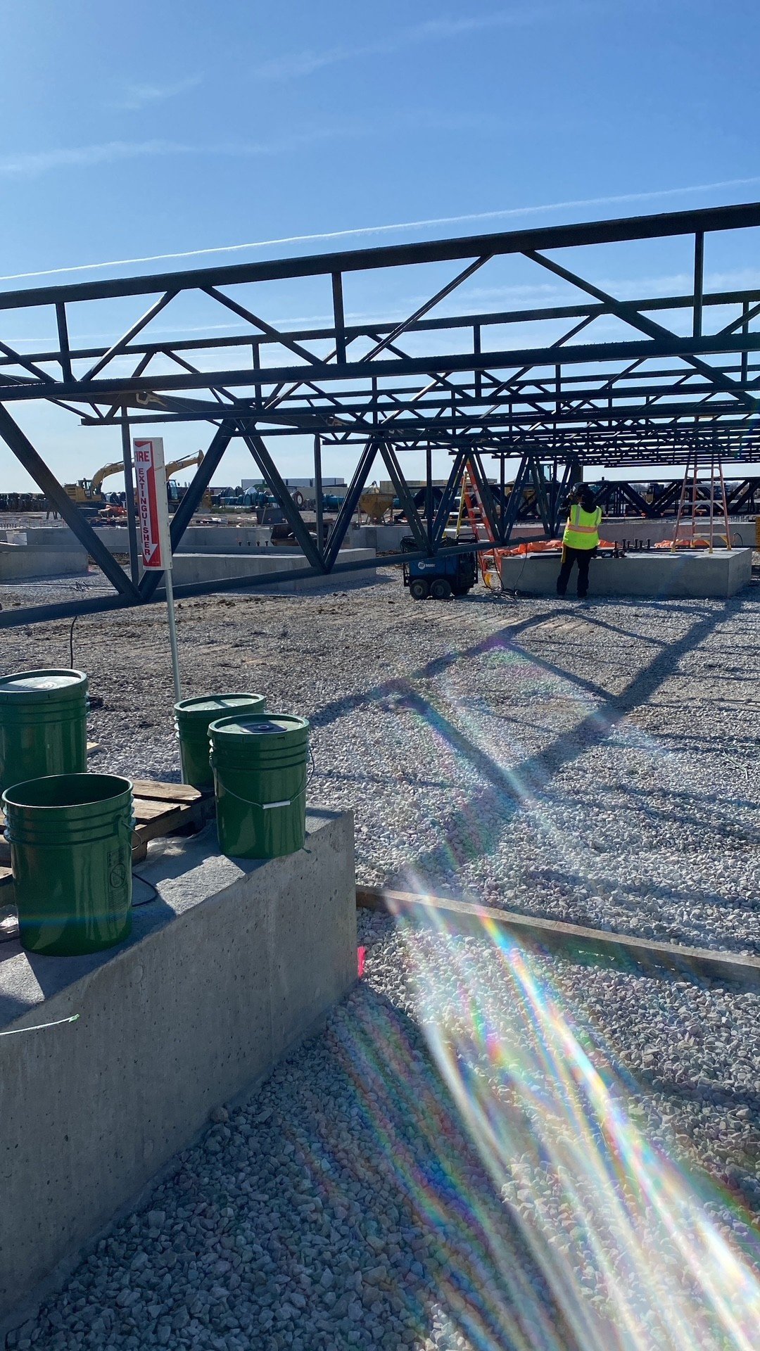 Construction site with metal framework, green buckets, and construction worker