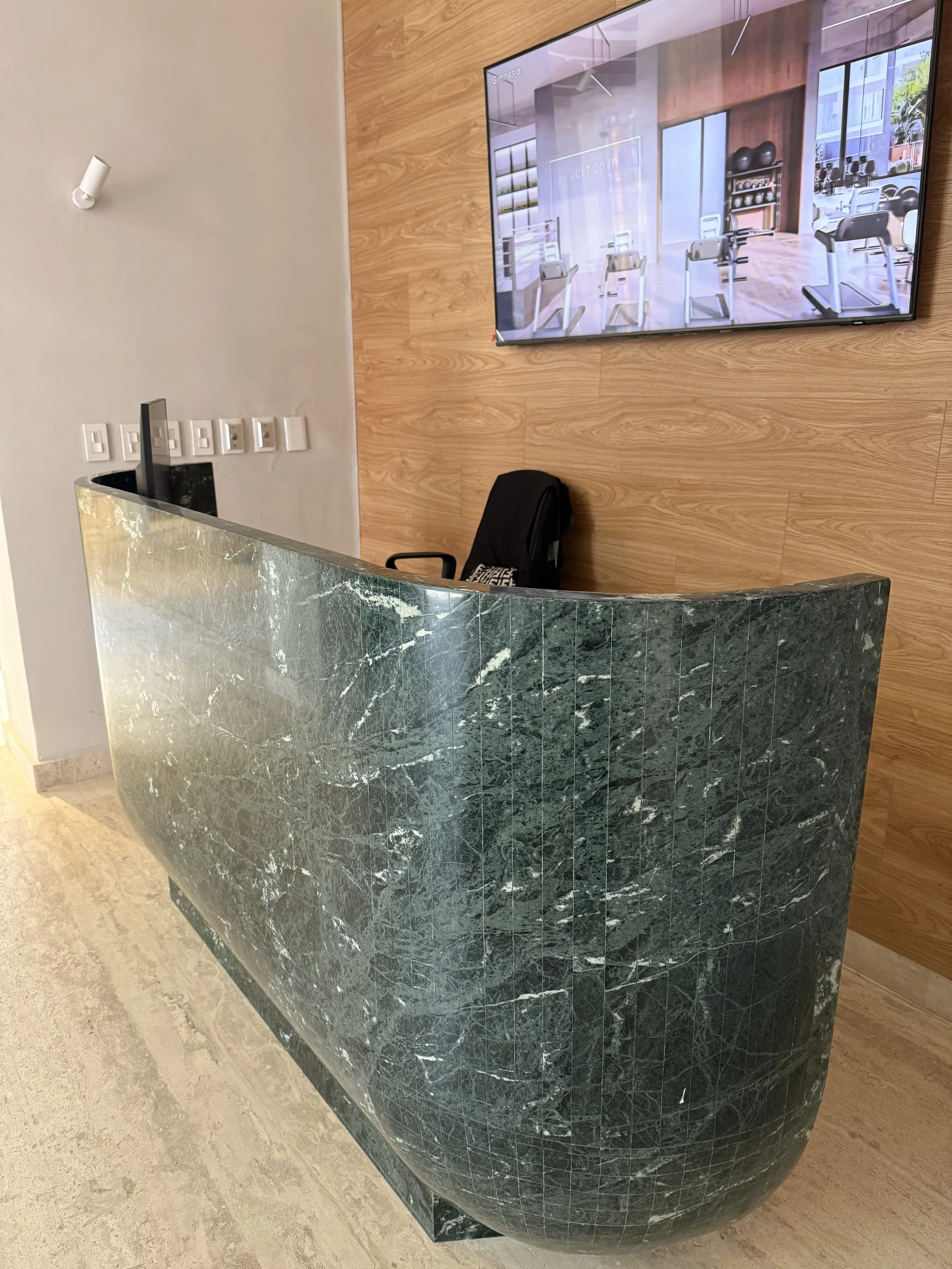 Mostrador de recepción de mármol verde en una oficina o gimnasio, con pared de madera y un televisor en la 
rmostrador de recepción hecho a la medida en mármol natural verde alpí