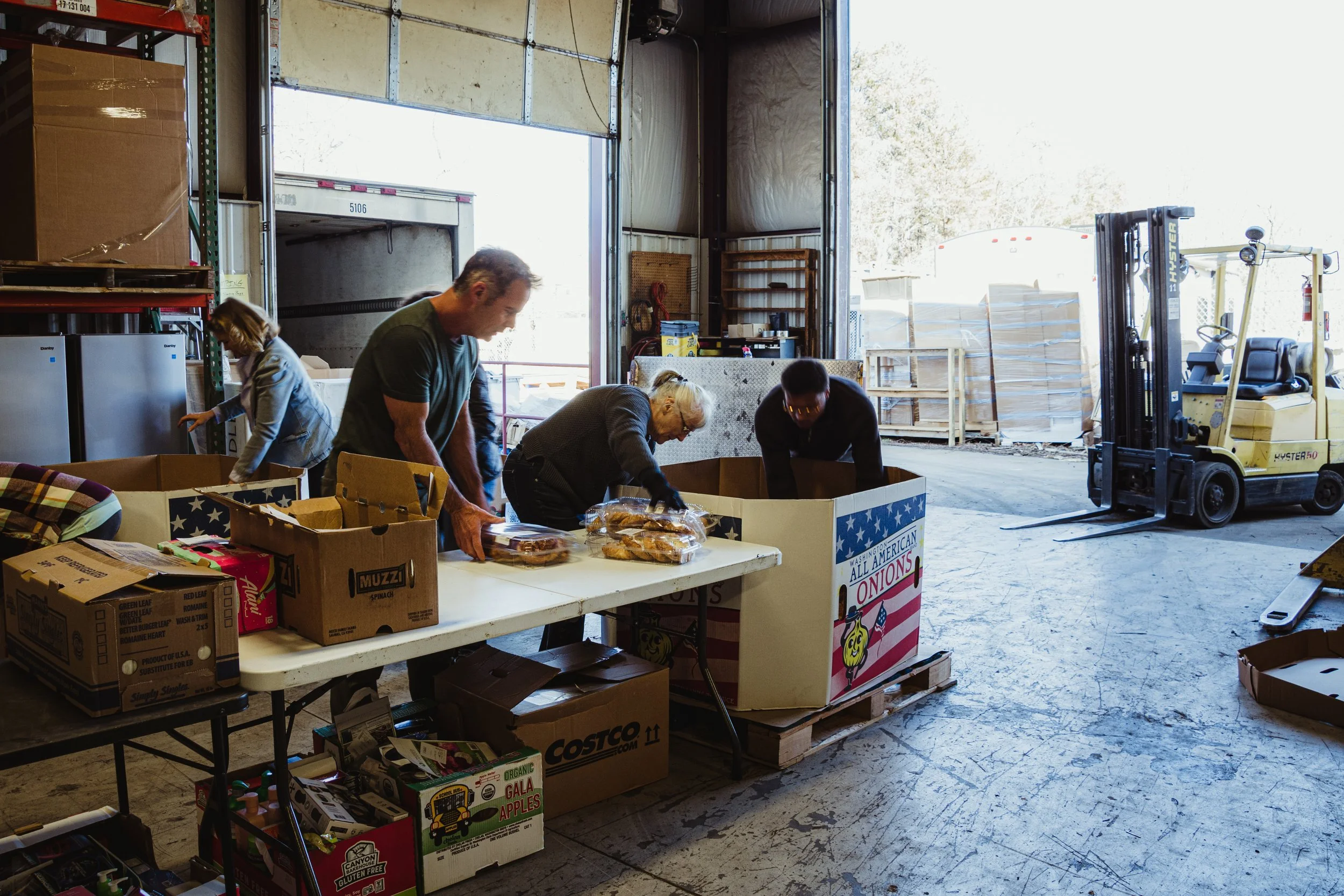 People packing boxes of food in a warehouse.