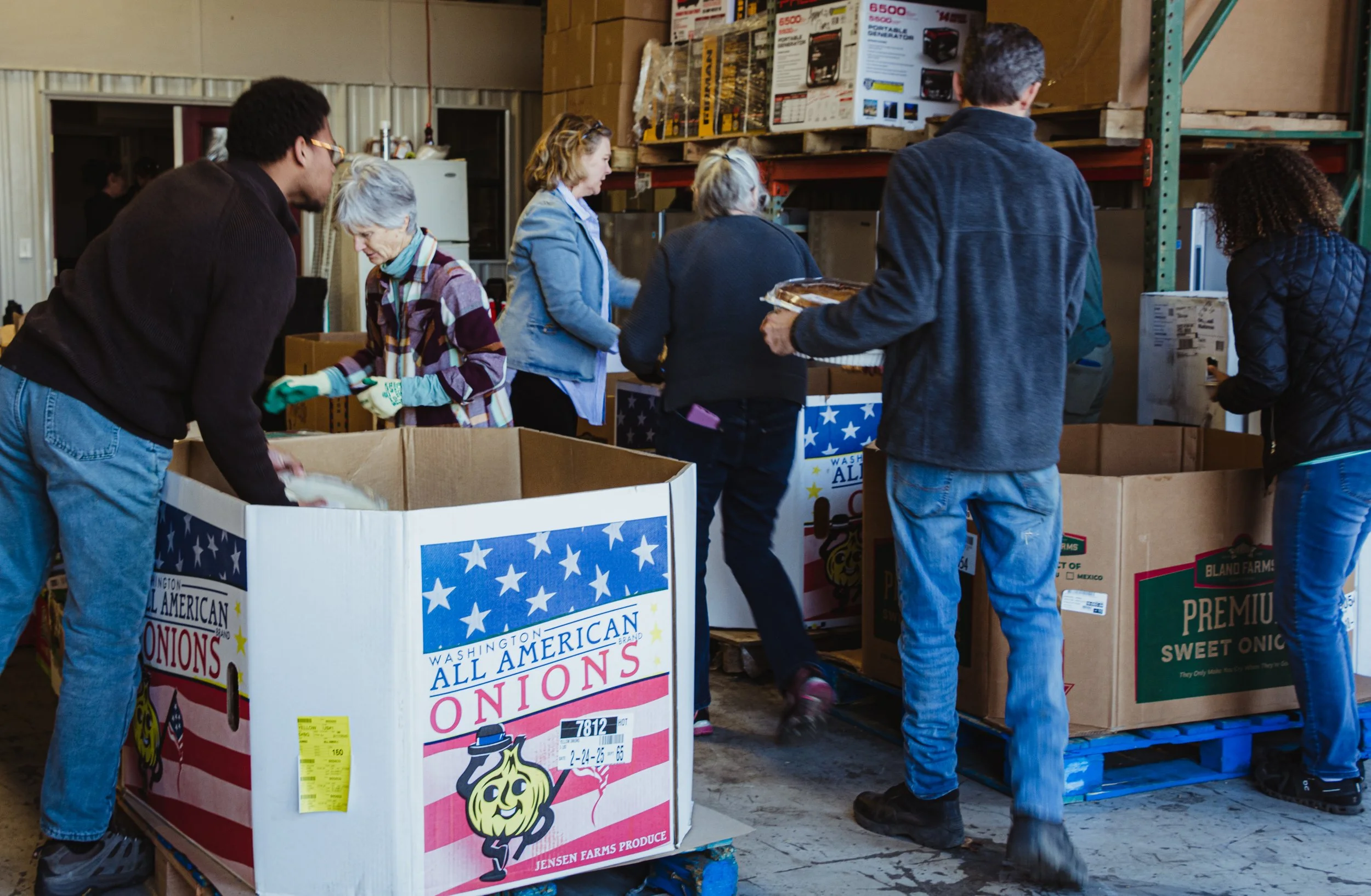 People sorting onions into boxes at a warehouse for a community event or distribution.