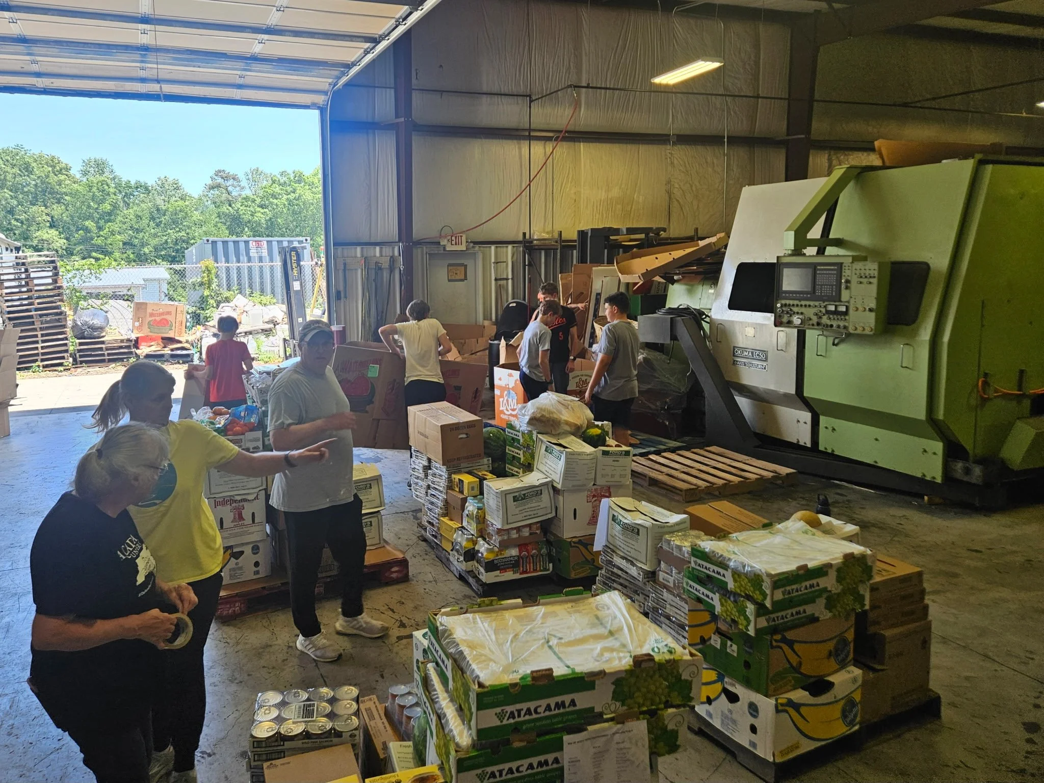 People unloading and organizing boxes of food and supplies inside a warehouse.