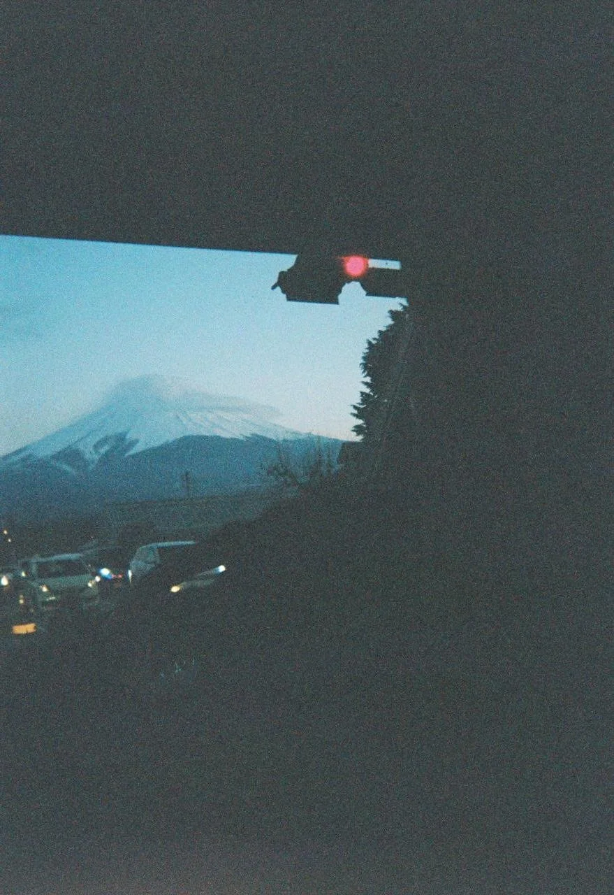 Vista desde el interior de un vehículo con el semáforo en rojo y una montaña cubierta de nieve al fondo.