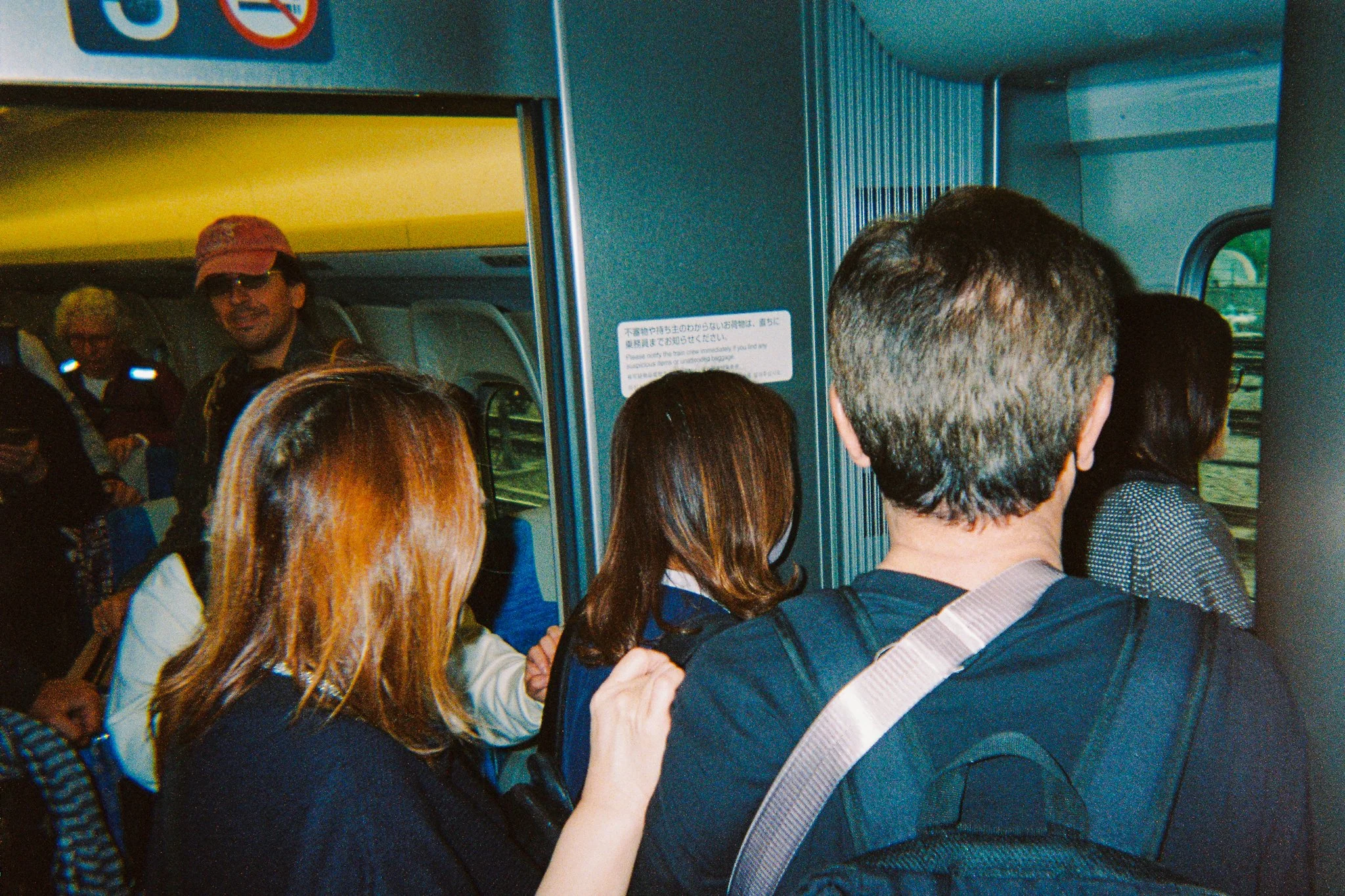 Grupo de personas haciendo fila para abordar un autobús en un aeropuerto o estación, algunas con mochilas y abrigos.