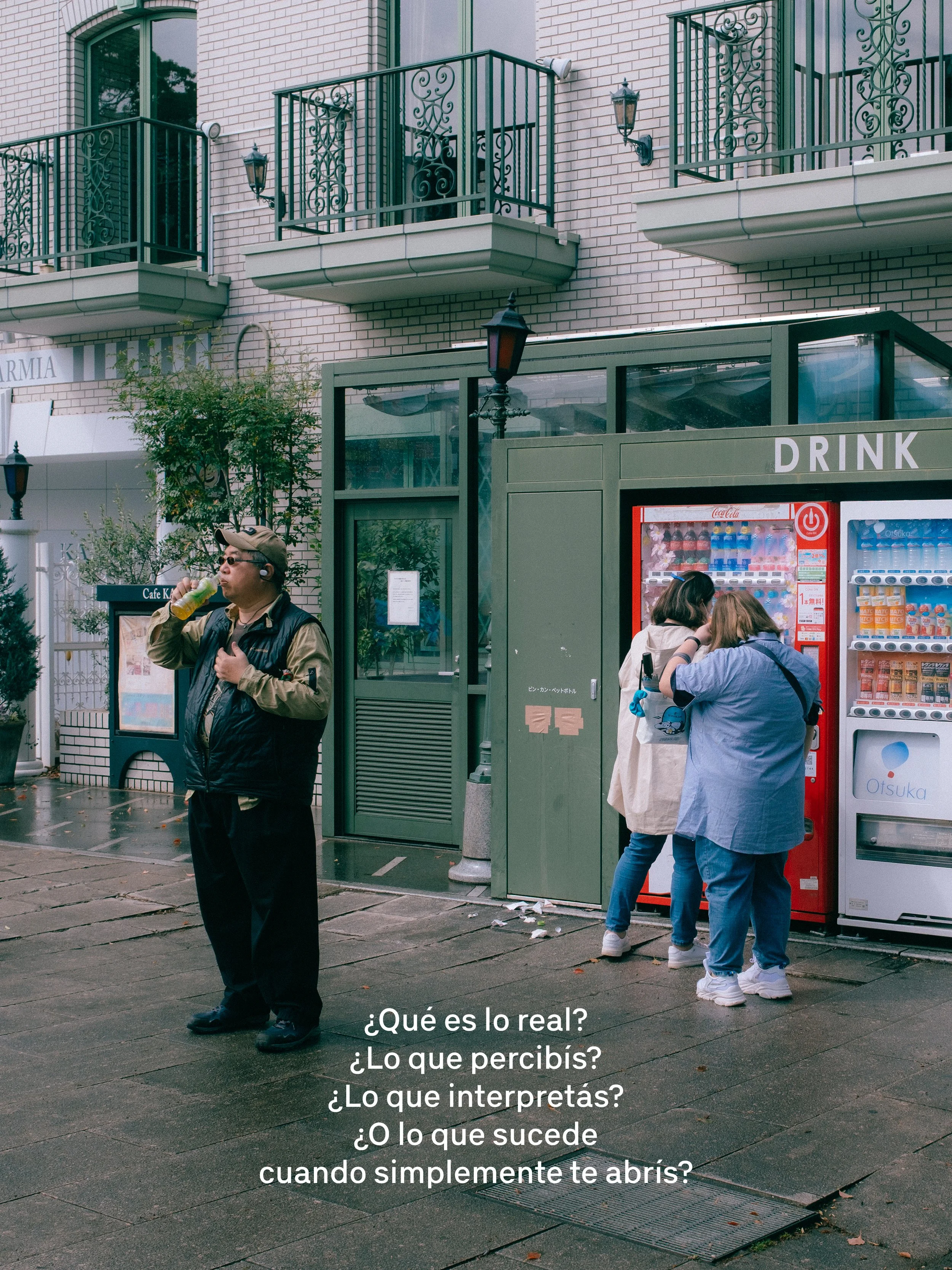 Personas en la calle cerca de una máquina expendedora y un puesto de bebidas. Al fondo, edificios con balcones de hierro. Frente a la máquina, hay varias personas, incluyendo una mujer con gafas y un hombre con casco, todos en movimiento.