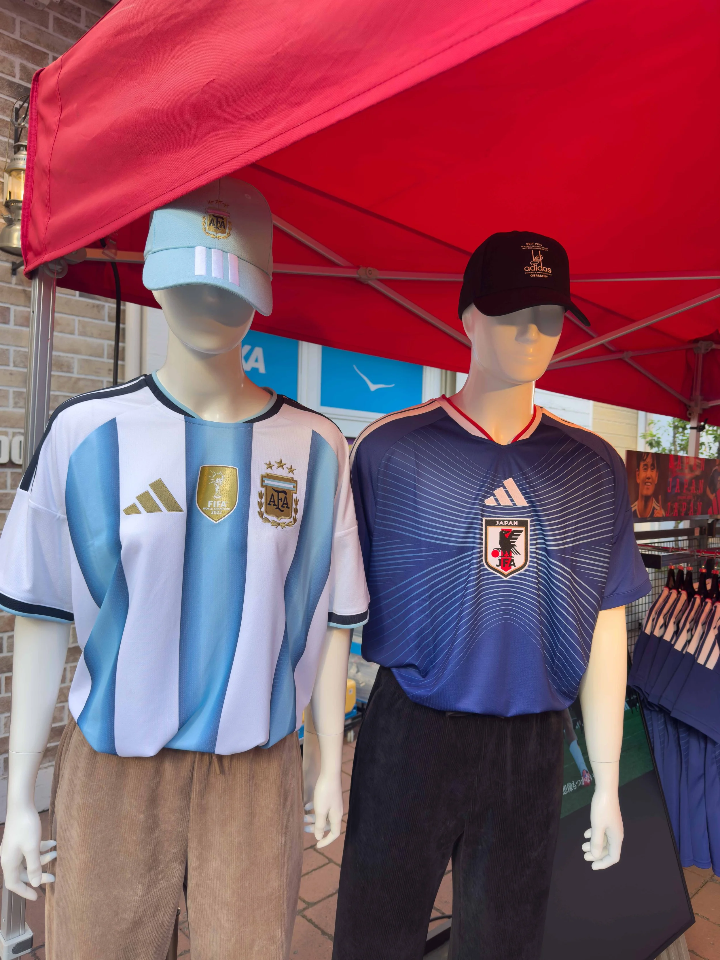 Maniquí con camiseta de fútbol de Argentina y gorra de la selección, junto a otro maniquí con camiseta de Japón y gorra