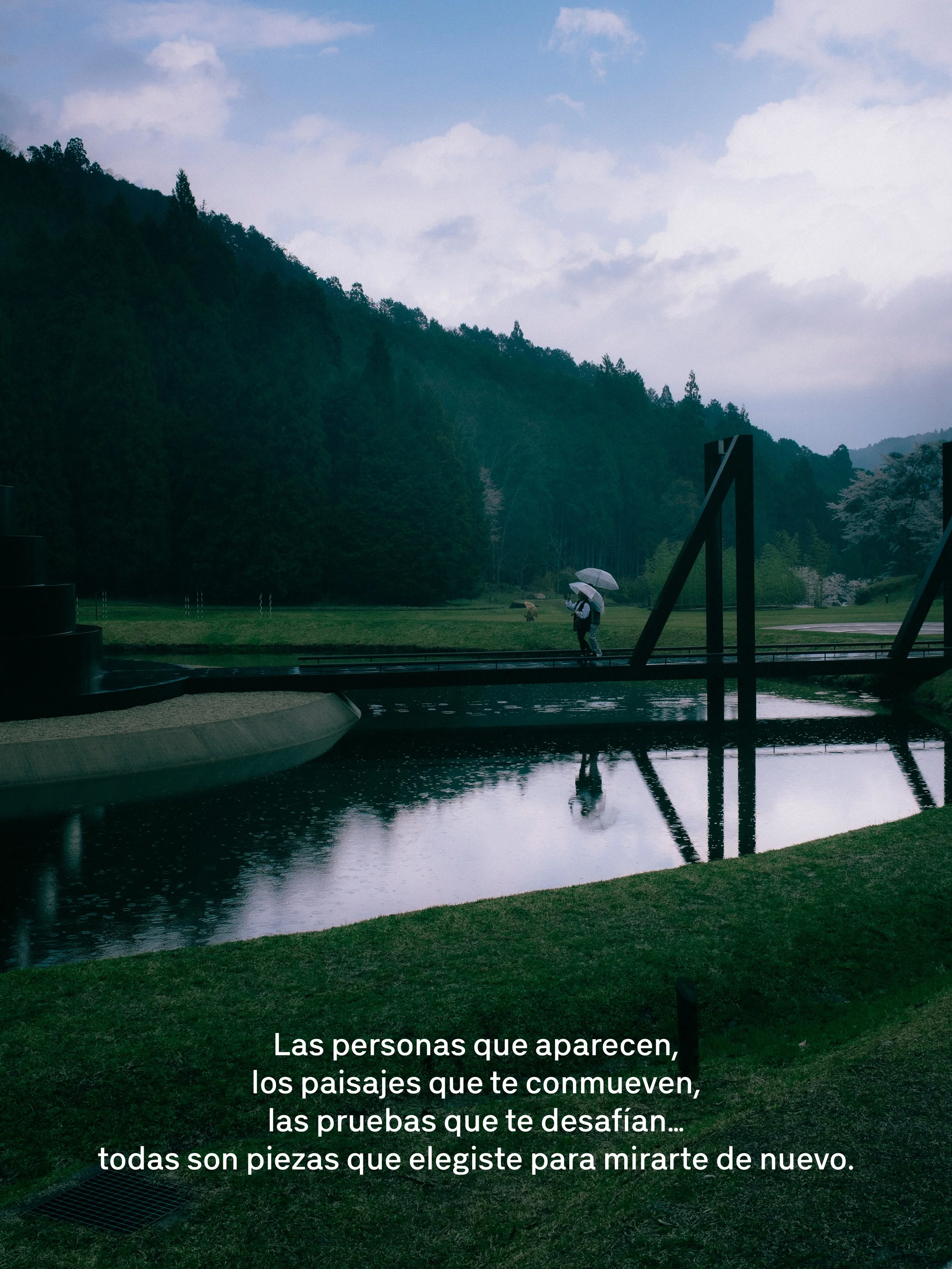 Paisaje lluvioso con árboles verdes, un estanque y personas con paraguas caminando. Texto en la parte inferior que dice: 'Las personas que aparecen, los paisajes que te conmueven, las pruebas que te desafían... todas son piezas que elegiste para mirarte de nuevo.'
