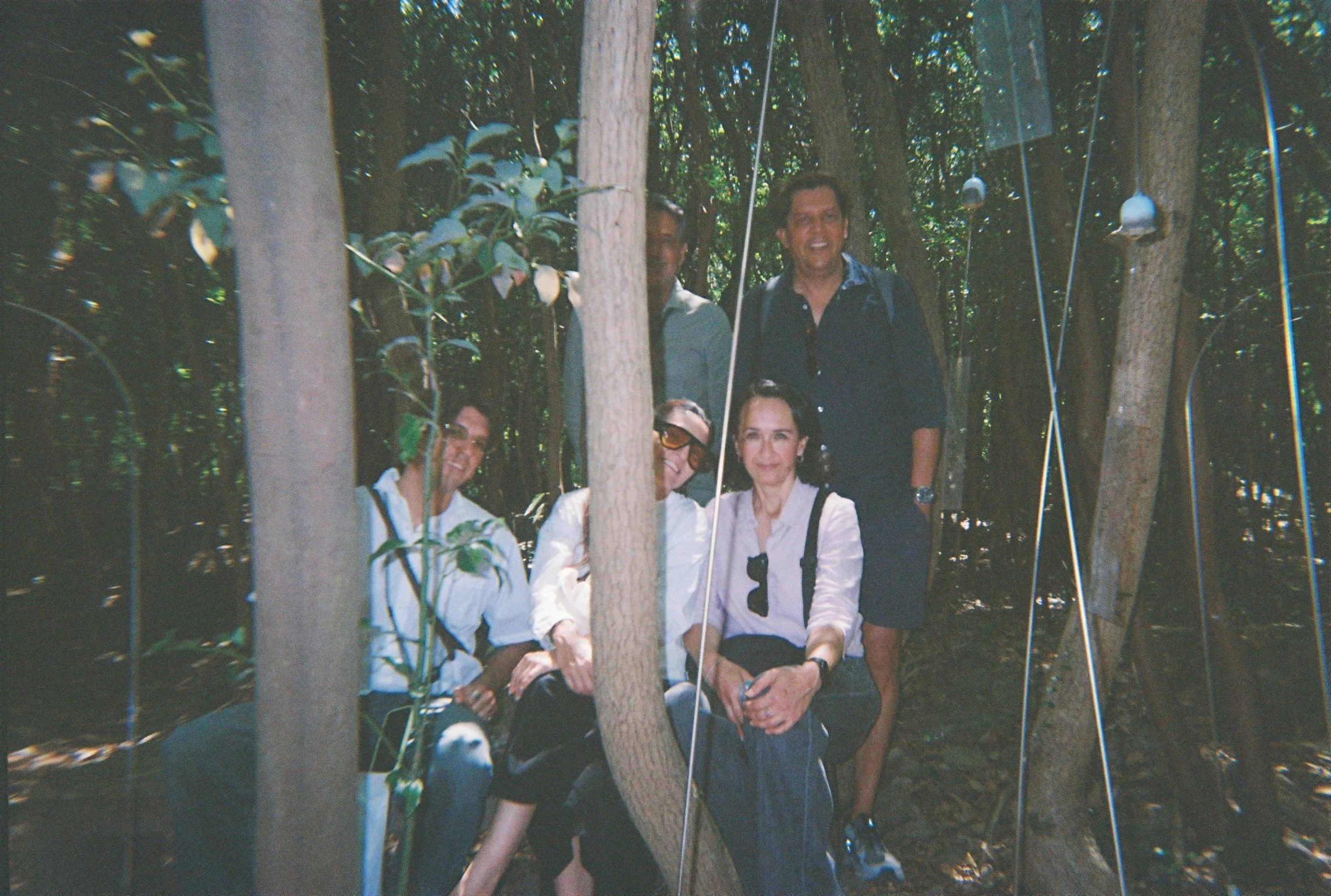 Grupo de cinco personas en un bosque, posando para una foto. Todos llevan ropa casual y parecen felices.