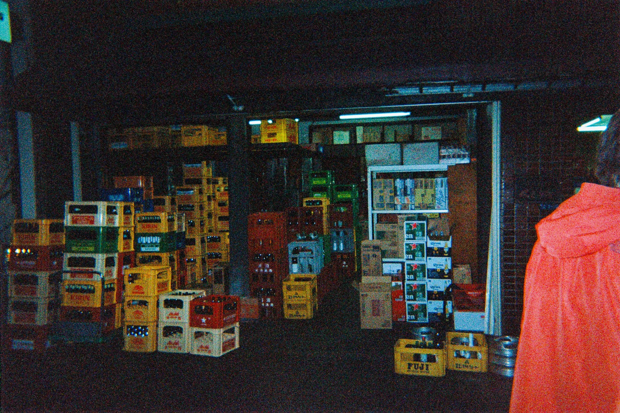 Estantería con varias cajas y botellas en una tienda en un entorno oscuro.