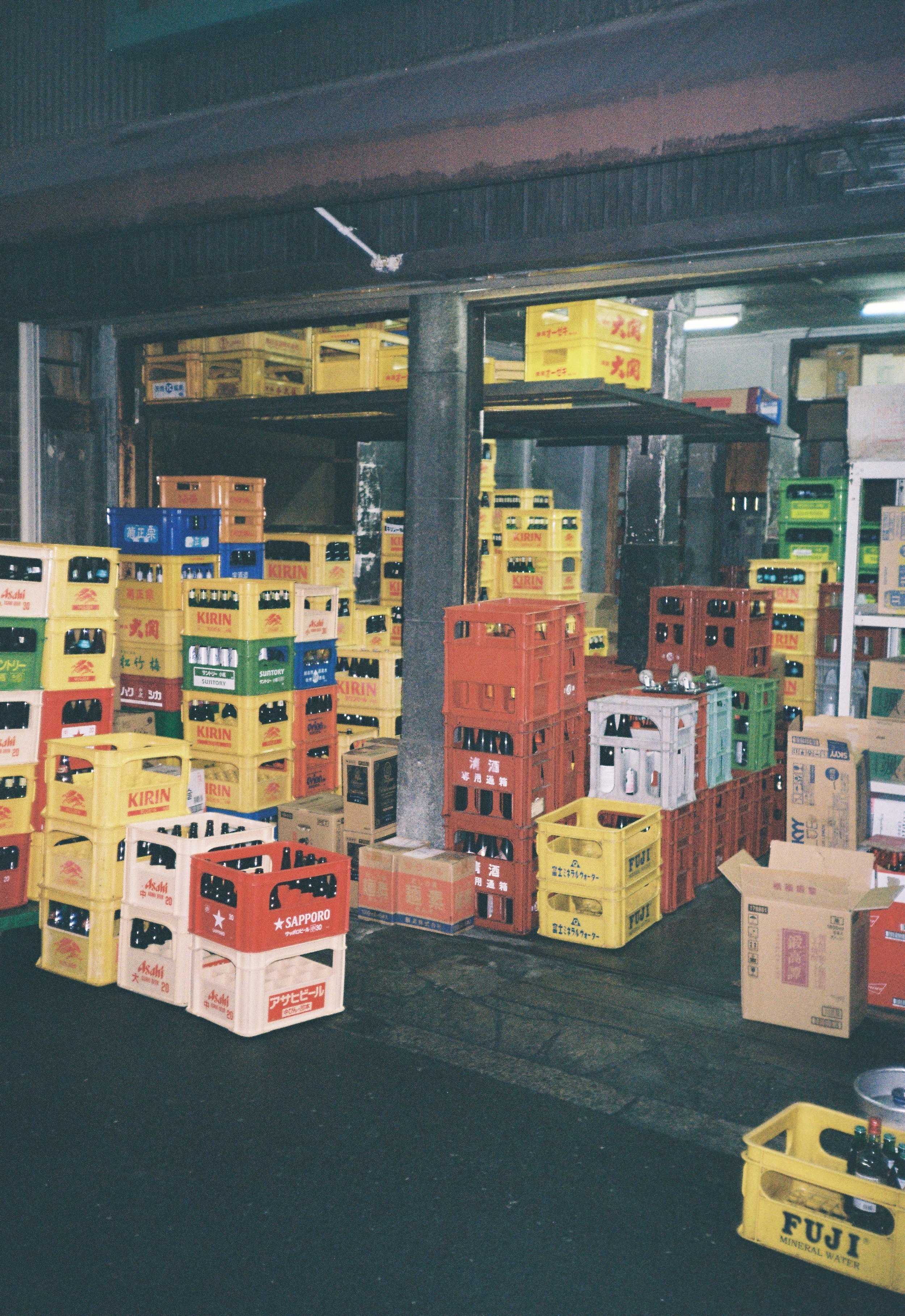 Estante con cajas y botellas, algunas en cajas de cartón, en un almacén o bodega industrial.