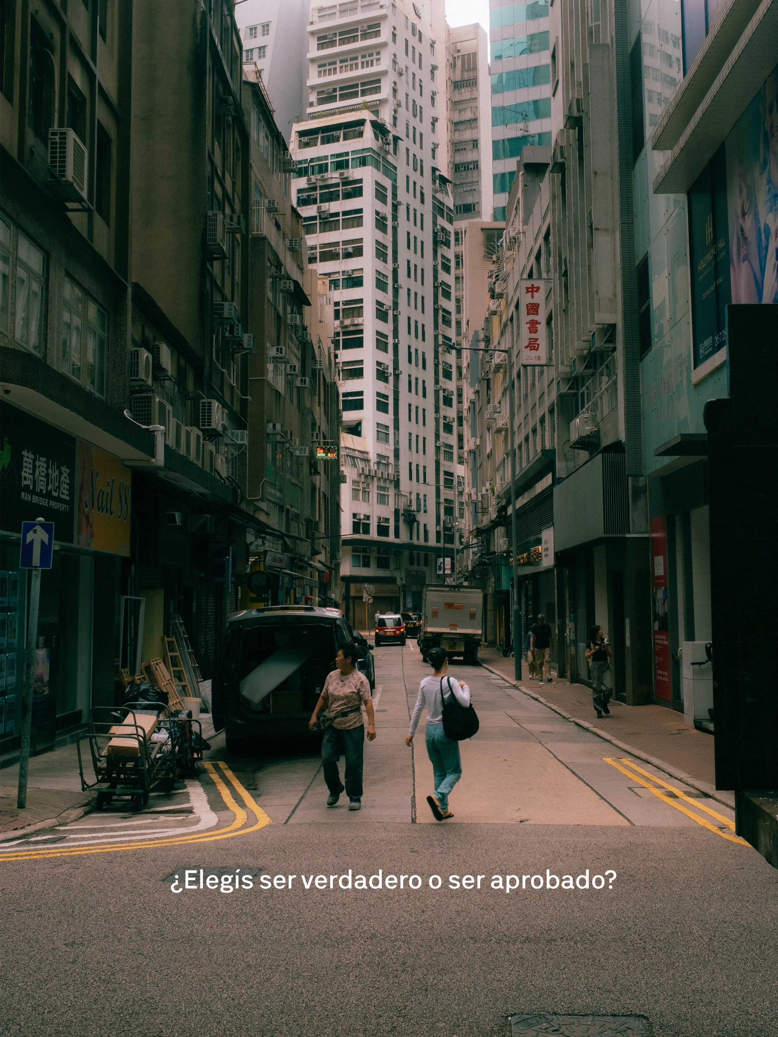 Vista de una calle en un área urbana con edificios altos y personas caminando. En la calle hay autos y un camión, y en las tiendas algunas letras en chino. La imagen tiene el texto sobre la calle que pregunta: '¿Elegís ser verdadero o ser aprobado?'.