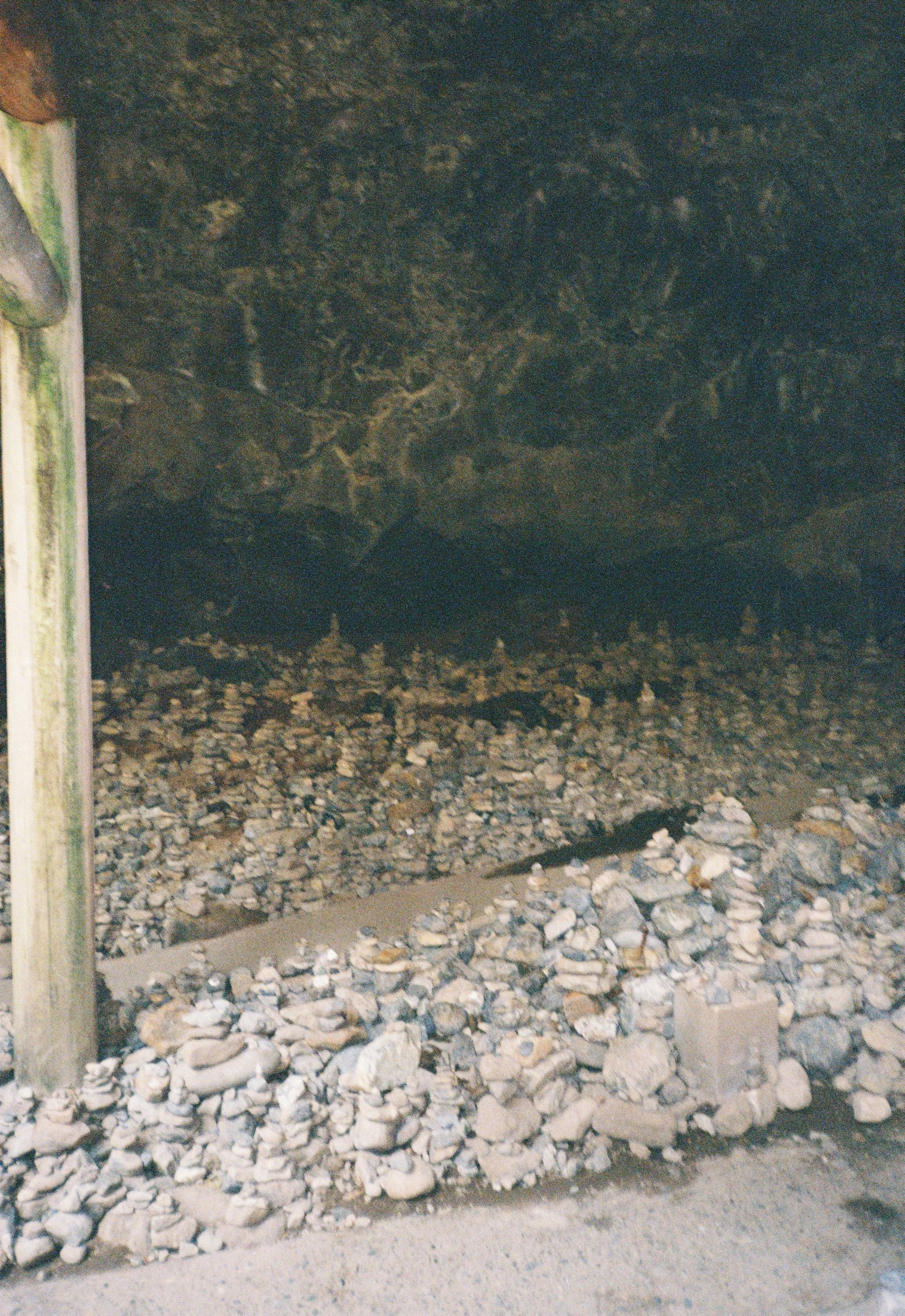 Una estructura de soporte de madera con paredes internas de bloques de piedra y tierra. La base está llena de piedras y grava, y hay una pequeña cavidad en el suelo frente a ella.
