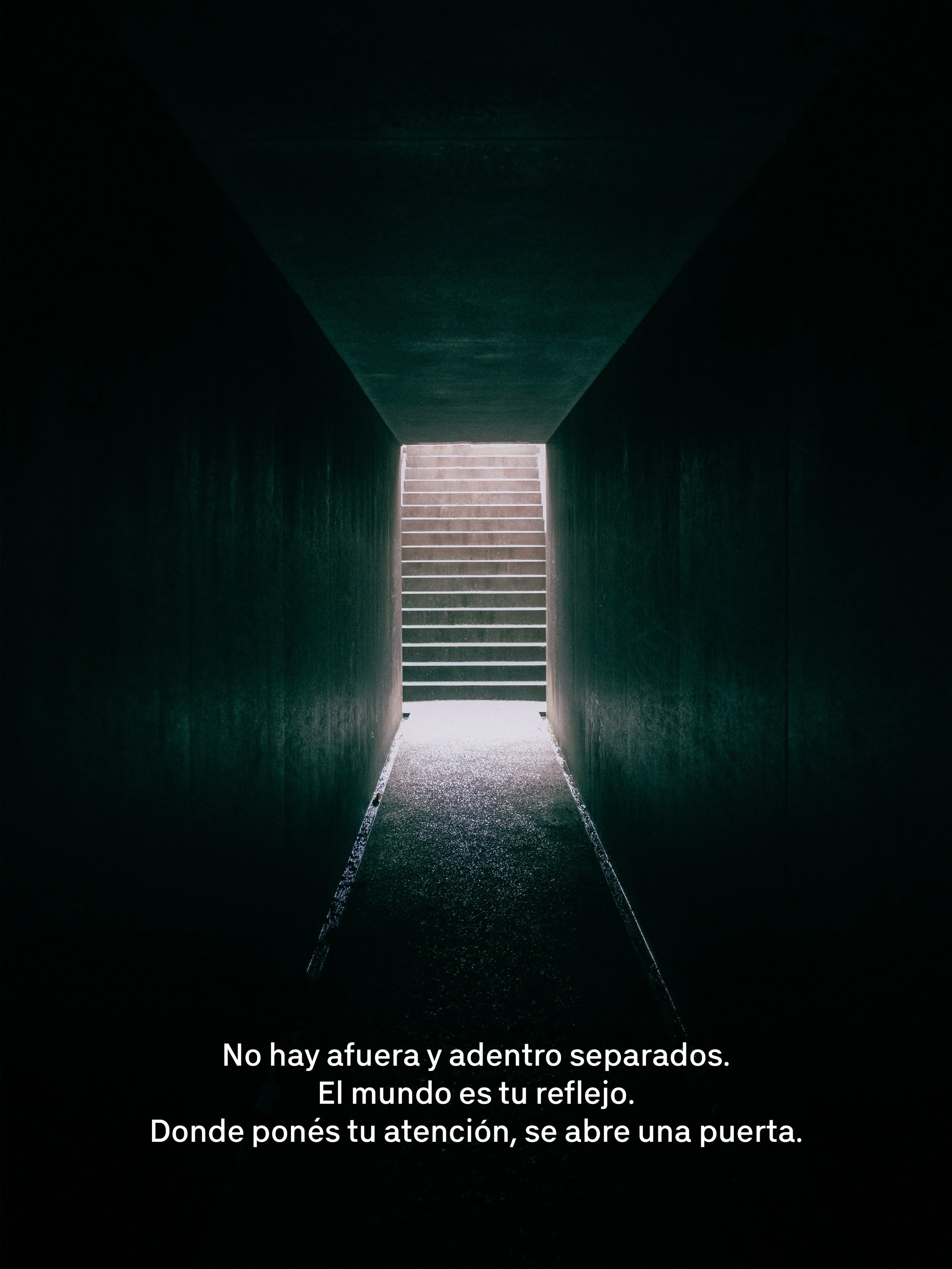 Una entrada oscura con escaleras iluminadas al fondo, dentro de un túnel o pasillo.