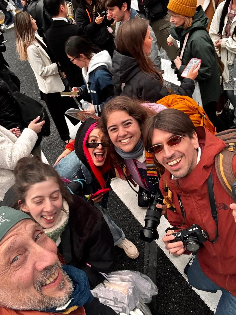 Grupo de personas felices tomando una selfie en una calle concurrida.