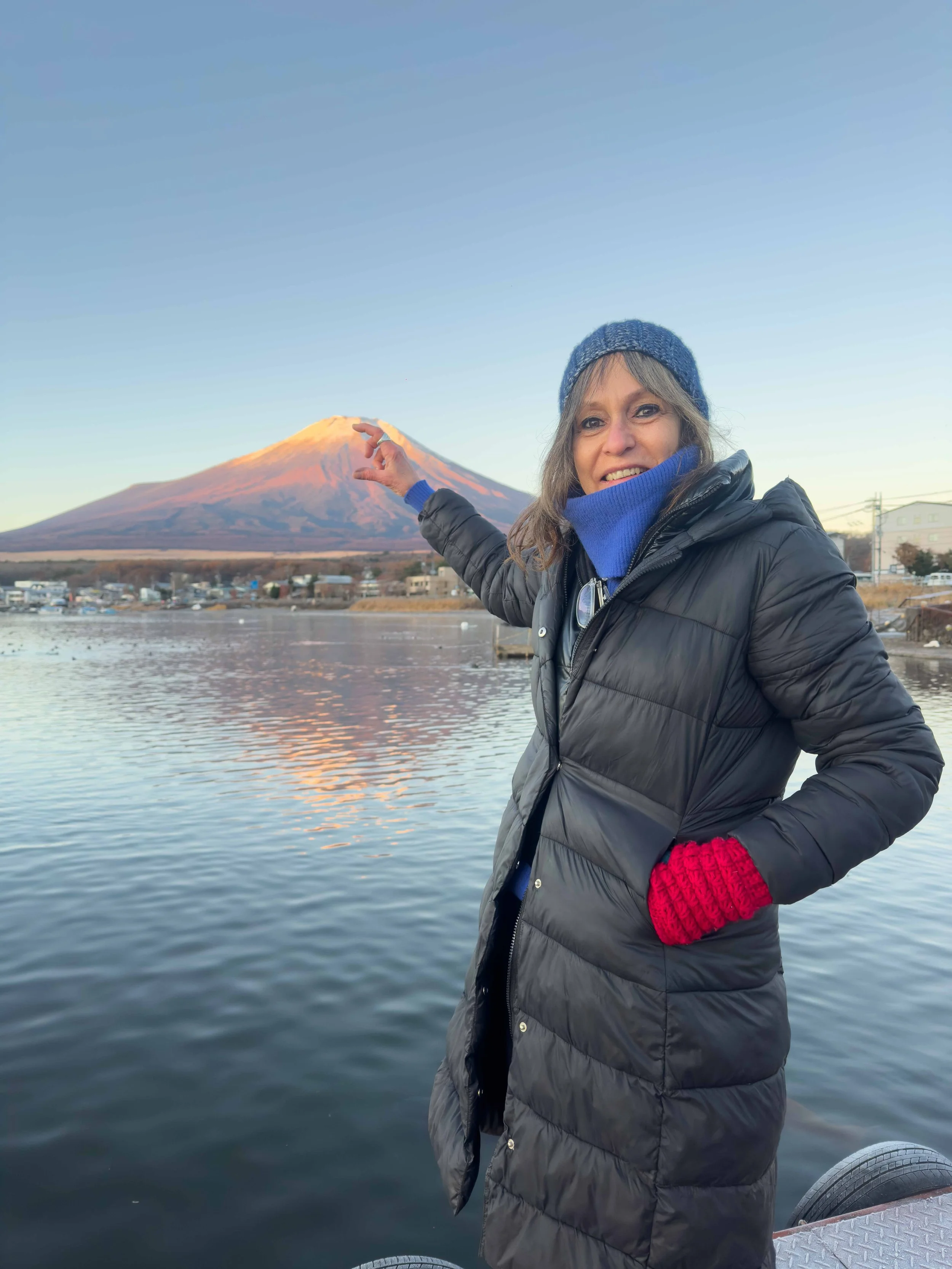Mujer sonriendo y señalando al volcán Concepción en Nicaragua, con agua y partes de un bote en primer plano.