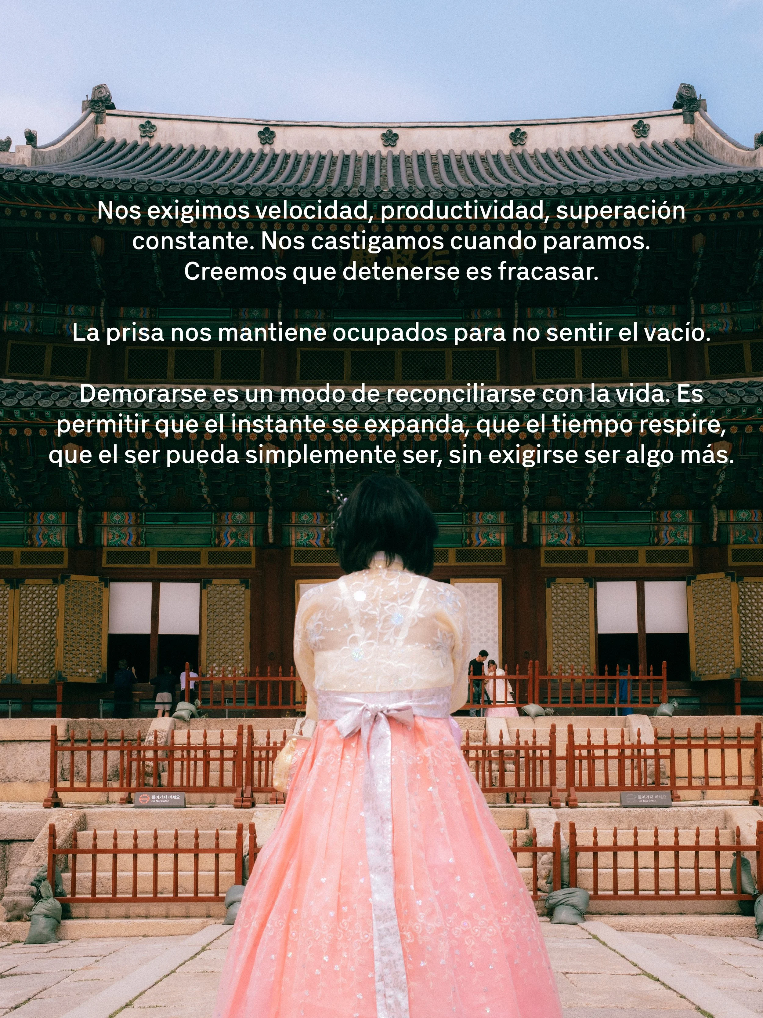 Una mujer usa un vestido tradicional rosa con detalles blancos, de espaldas, en un templo de arquitectura asiática antigua, con un fondo de techo de tejas y decoraciones florales.