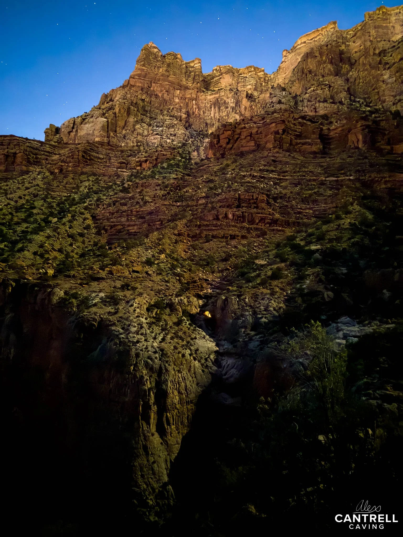 A rugged, illuminated canyon at night with starry sky.