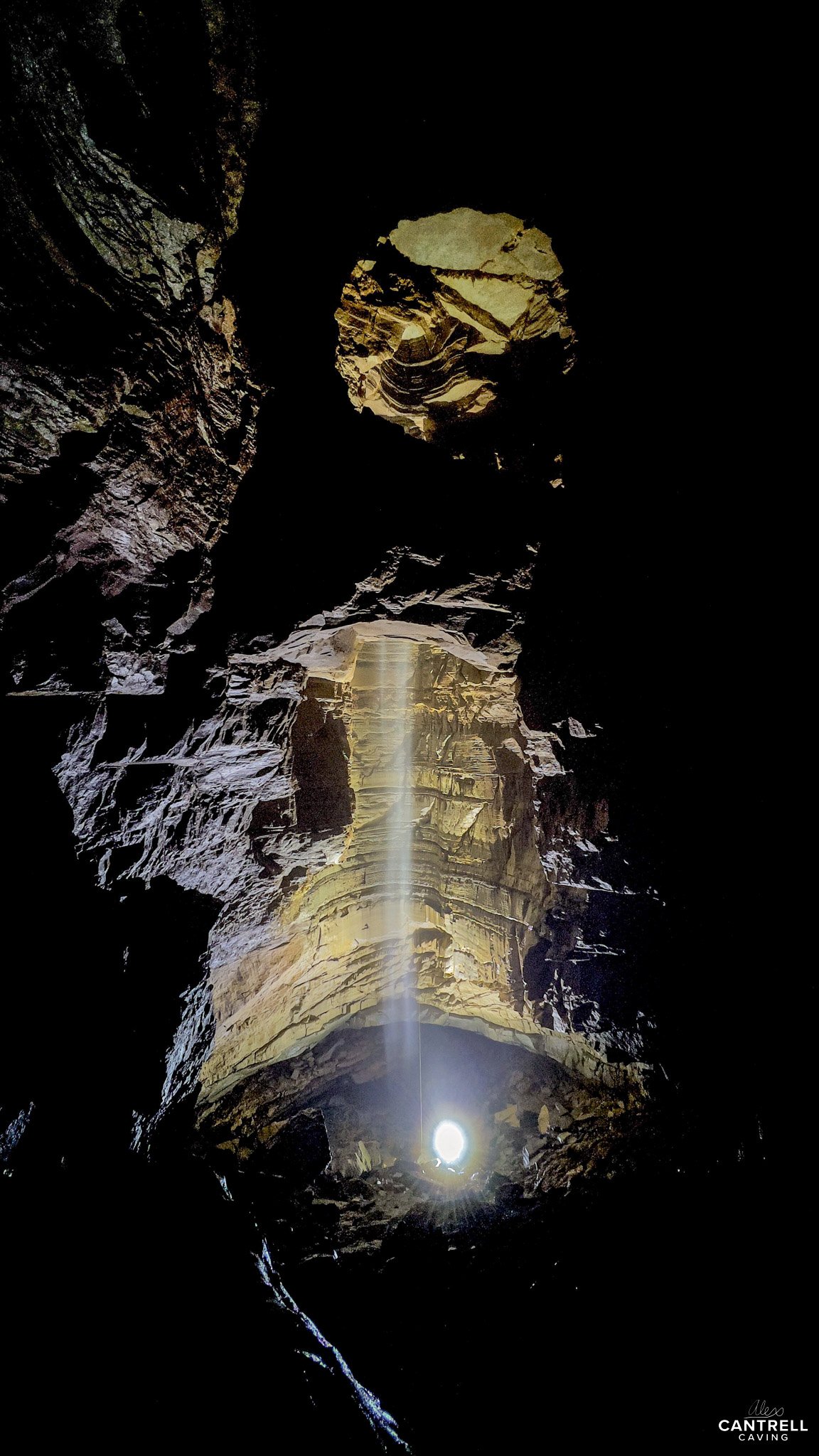Sunlight streaming through a circular opening in a cave, illuminating the rocky interior walls.