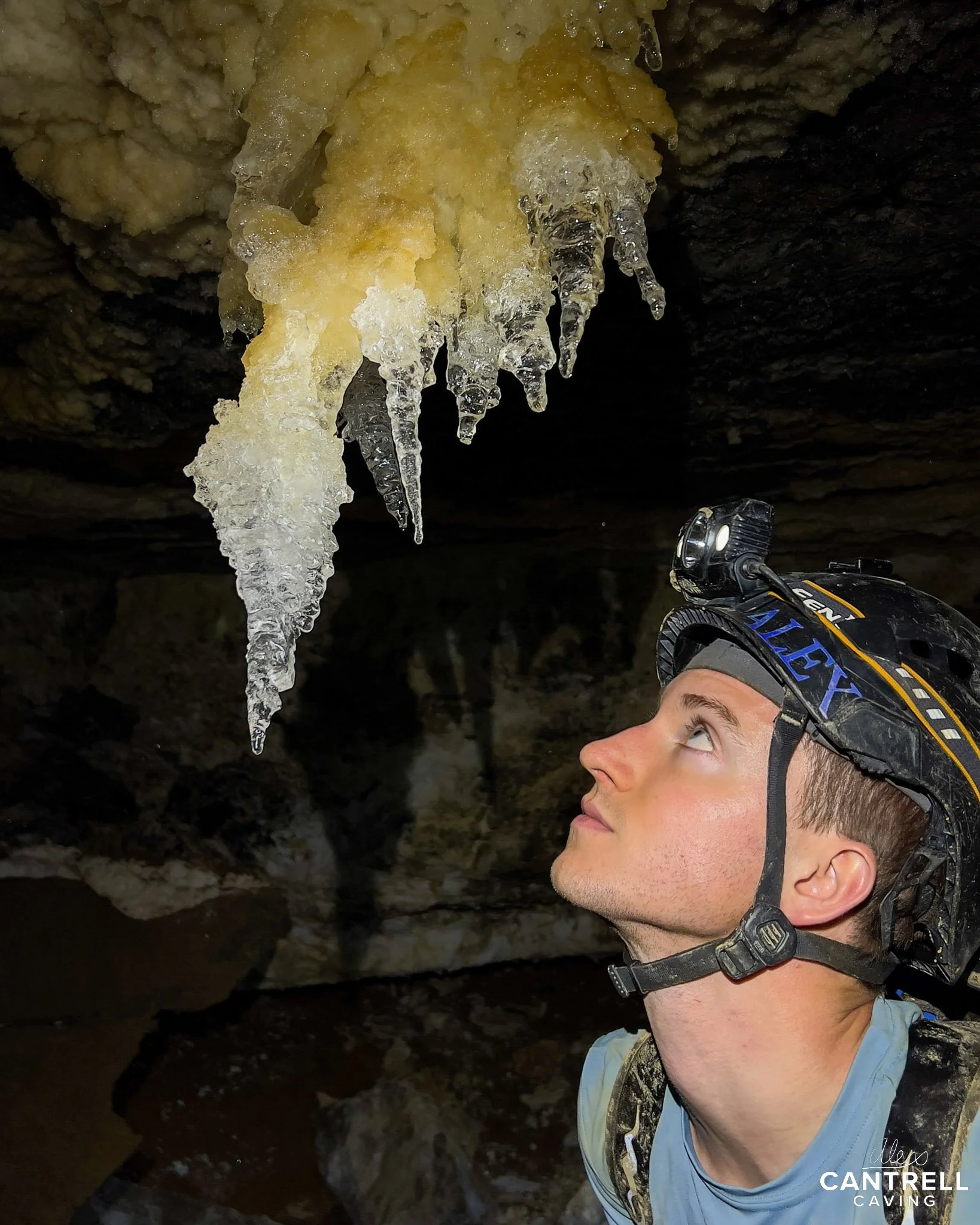 Caver in helmet looking at cave formation.