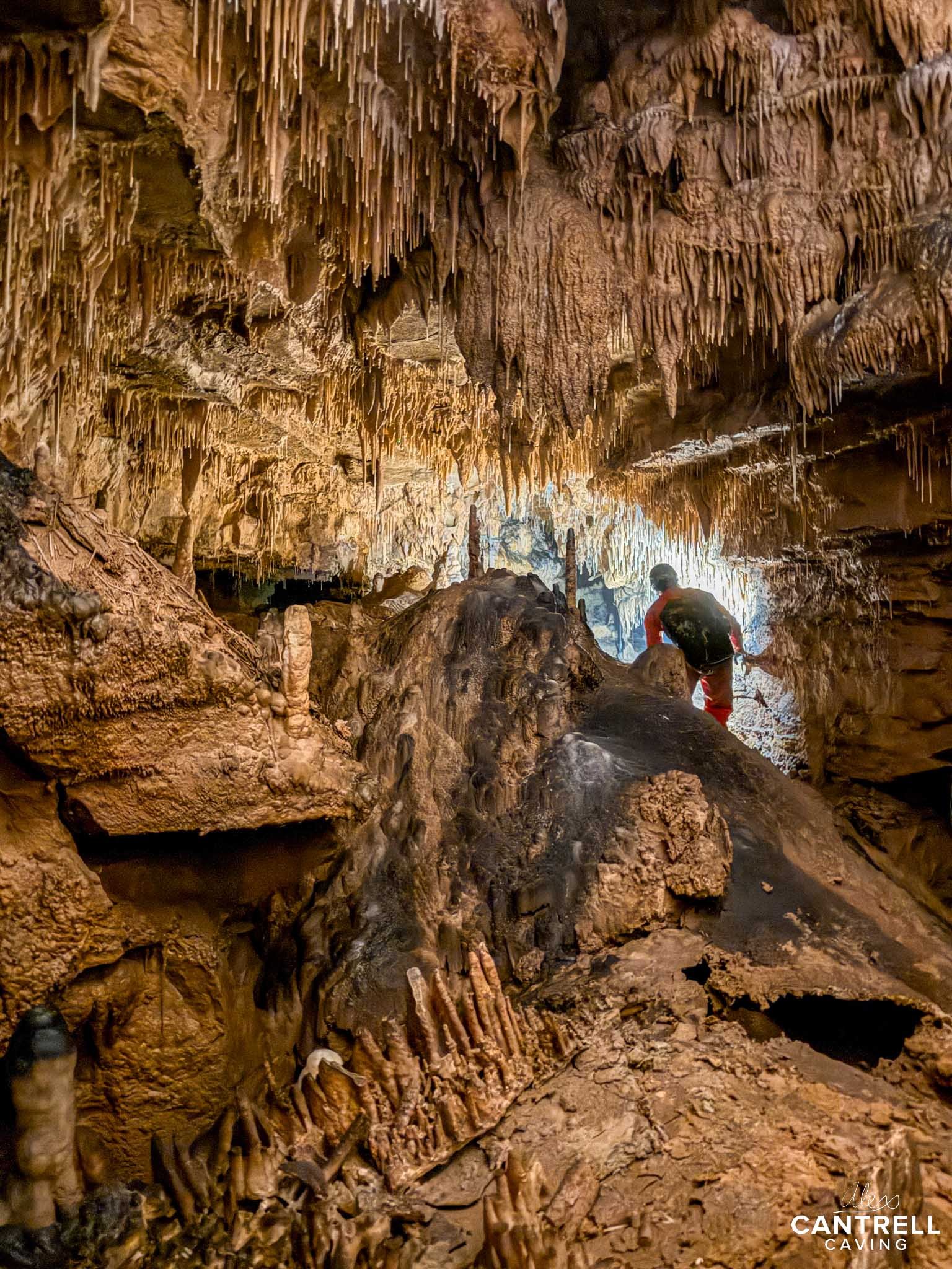 Person exploring a cave with stalactites and stalagmites