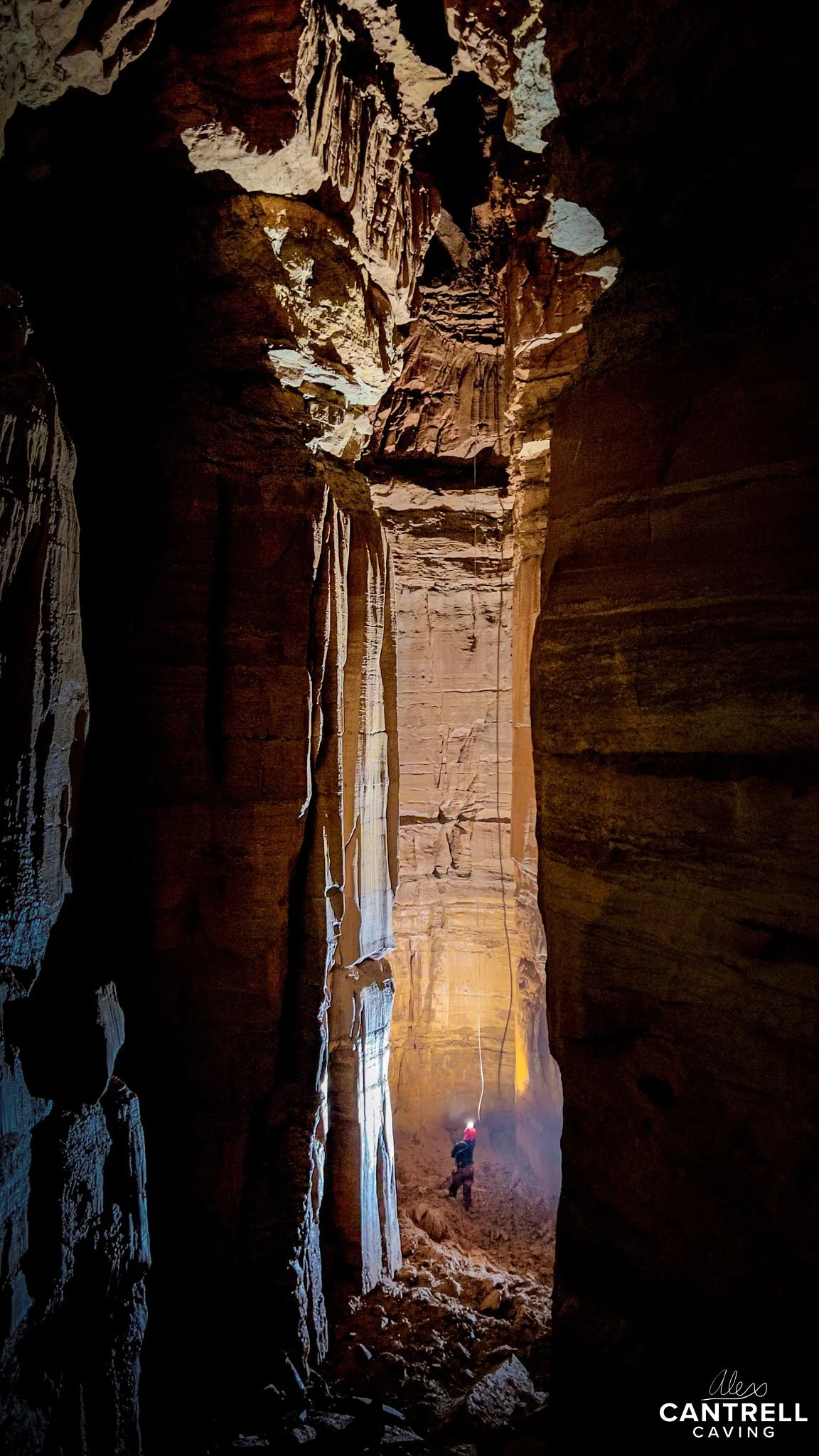 Cave with a person rock climbing inside.