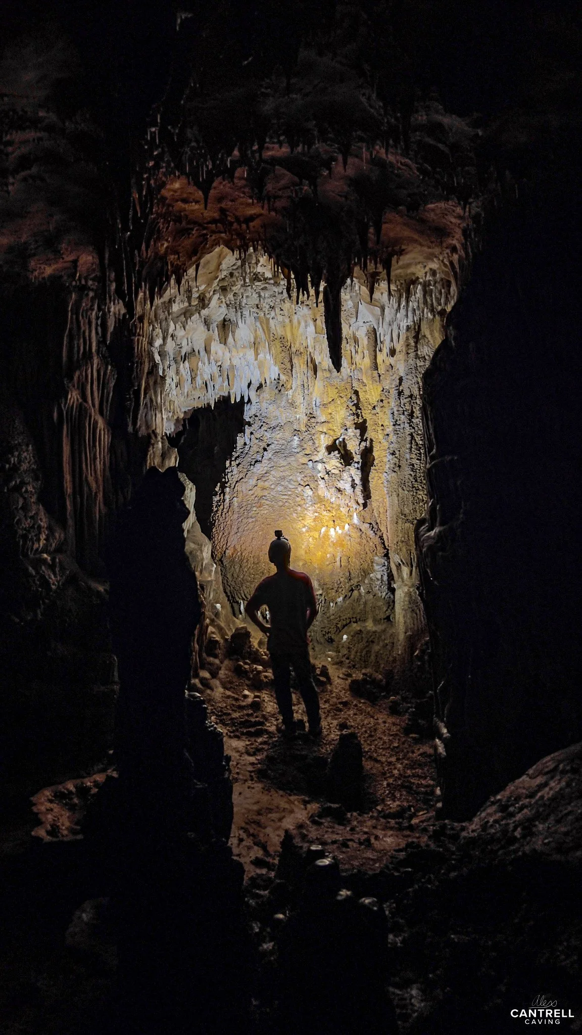 Person exploring a cave with stalactites and stalagmites