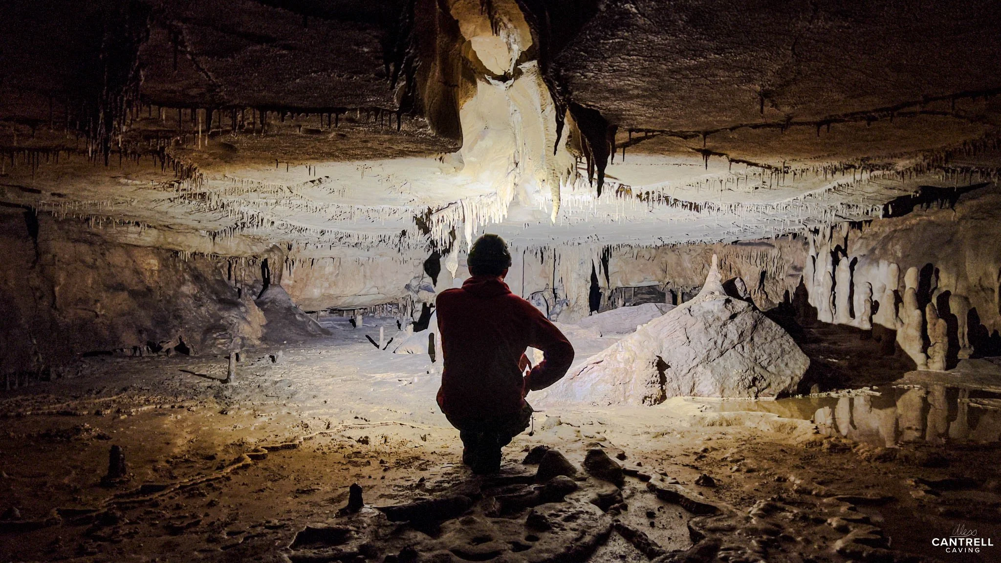 Person exploring a cave with stalactites and rock formations