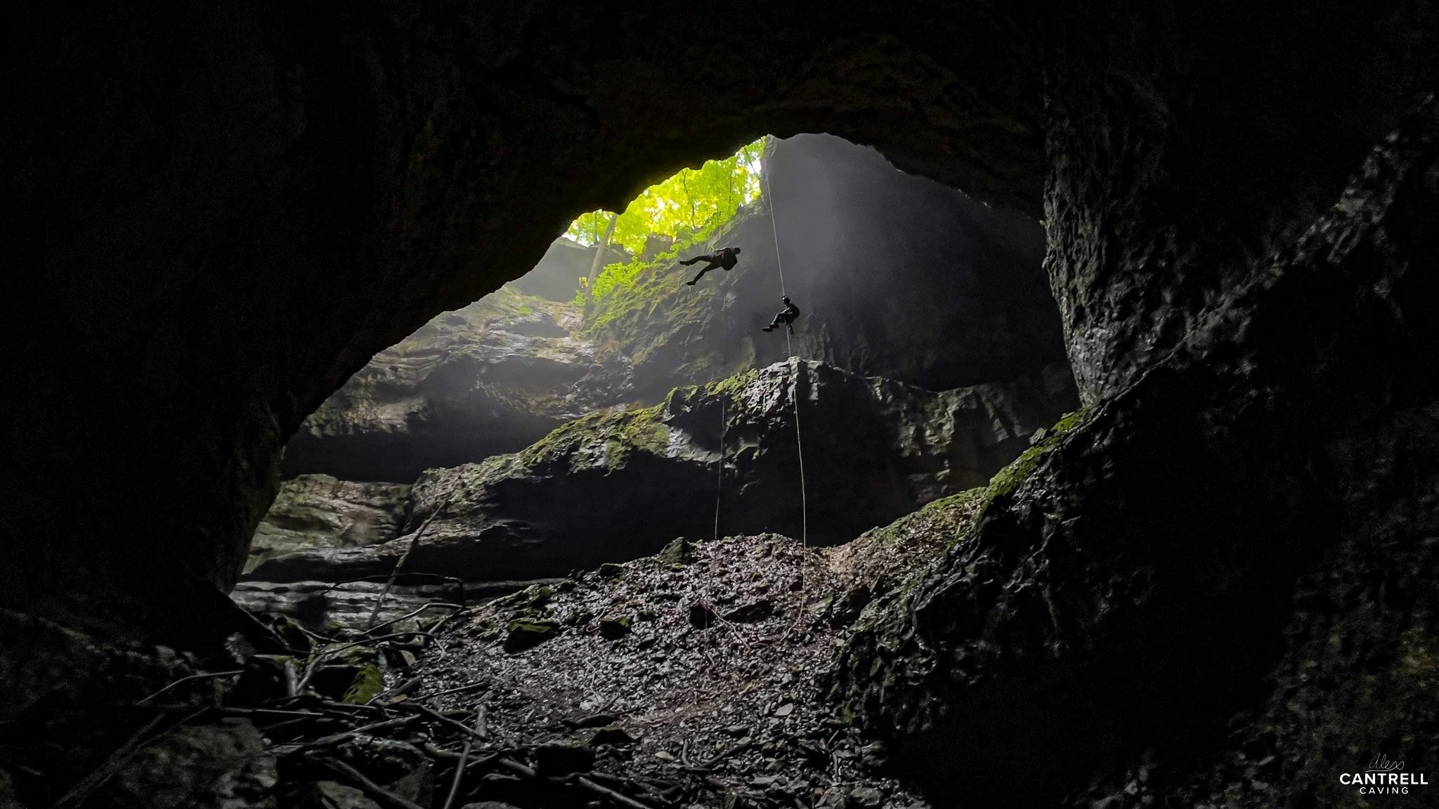 Cave entrance with two people rappelling.
