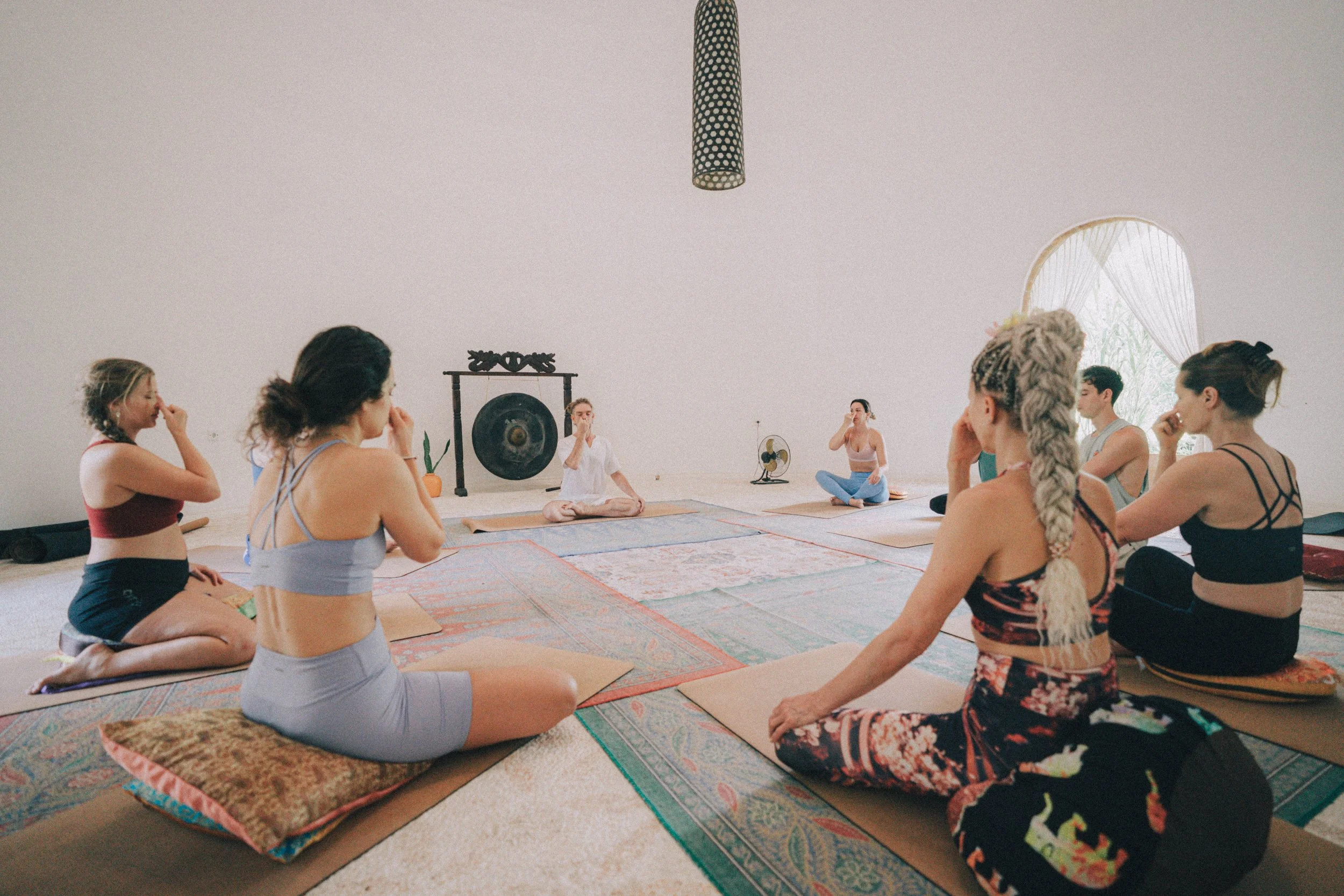 Yoga teacher training student practising Nadi Shodhana alternate nostril breathing during pranayama class in Bali